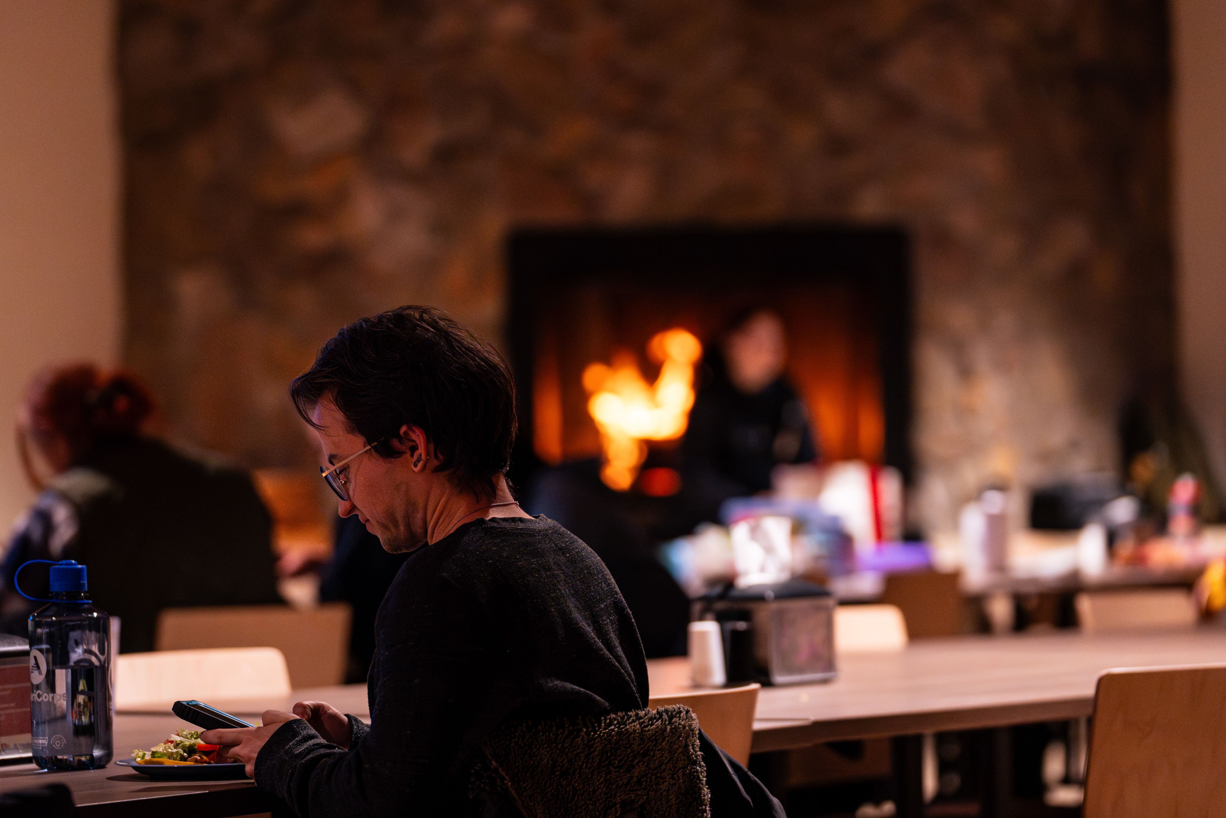 A man sitting in front of a fireplace at Kennedy Mountain Campus