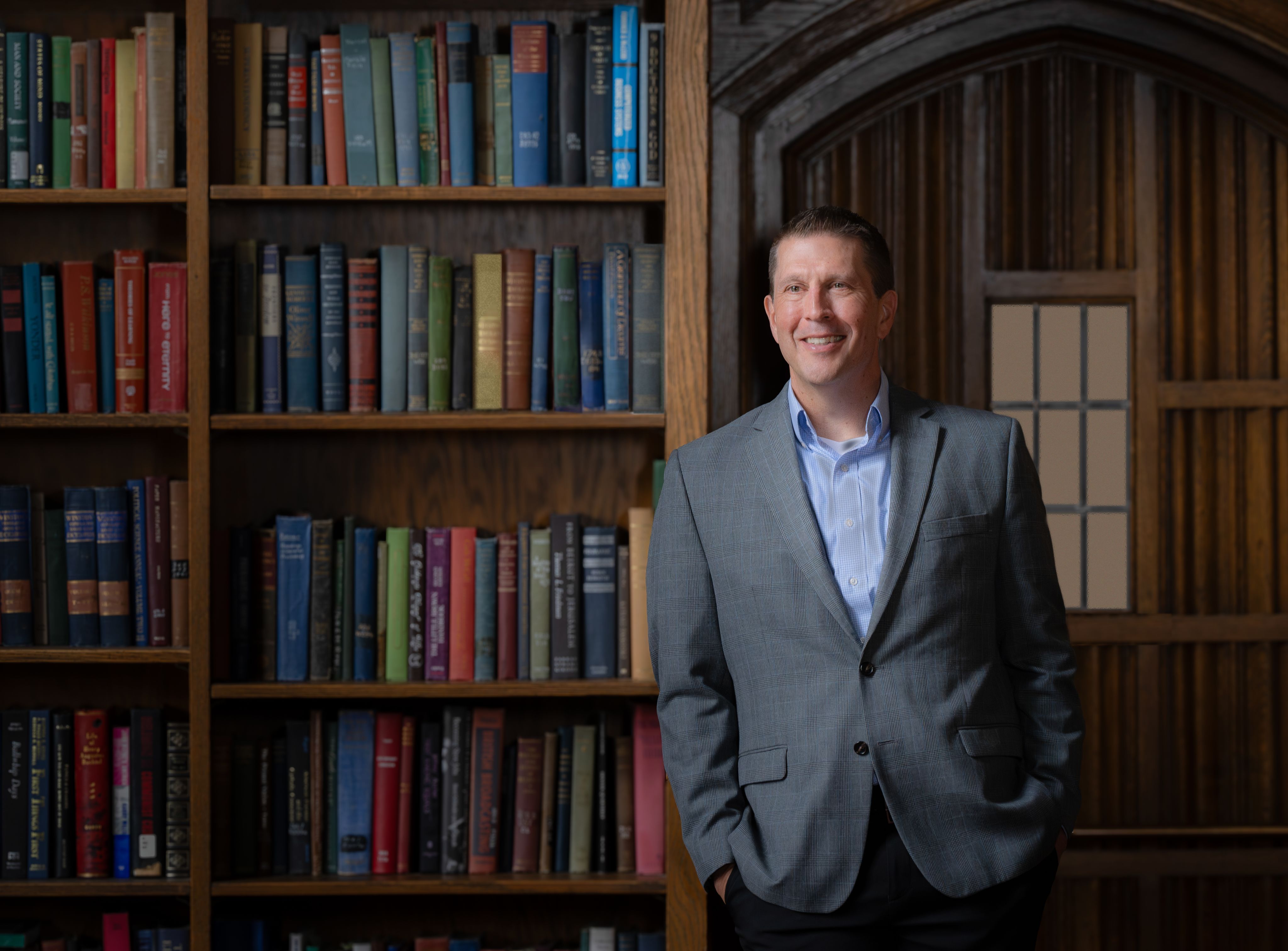 senior vice chancellor for university relations Brad Bohlander in a grey jacket with bookshelves in the background