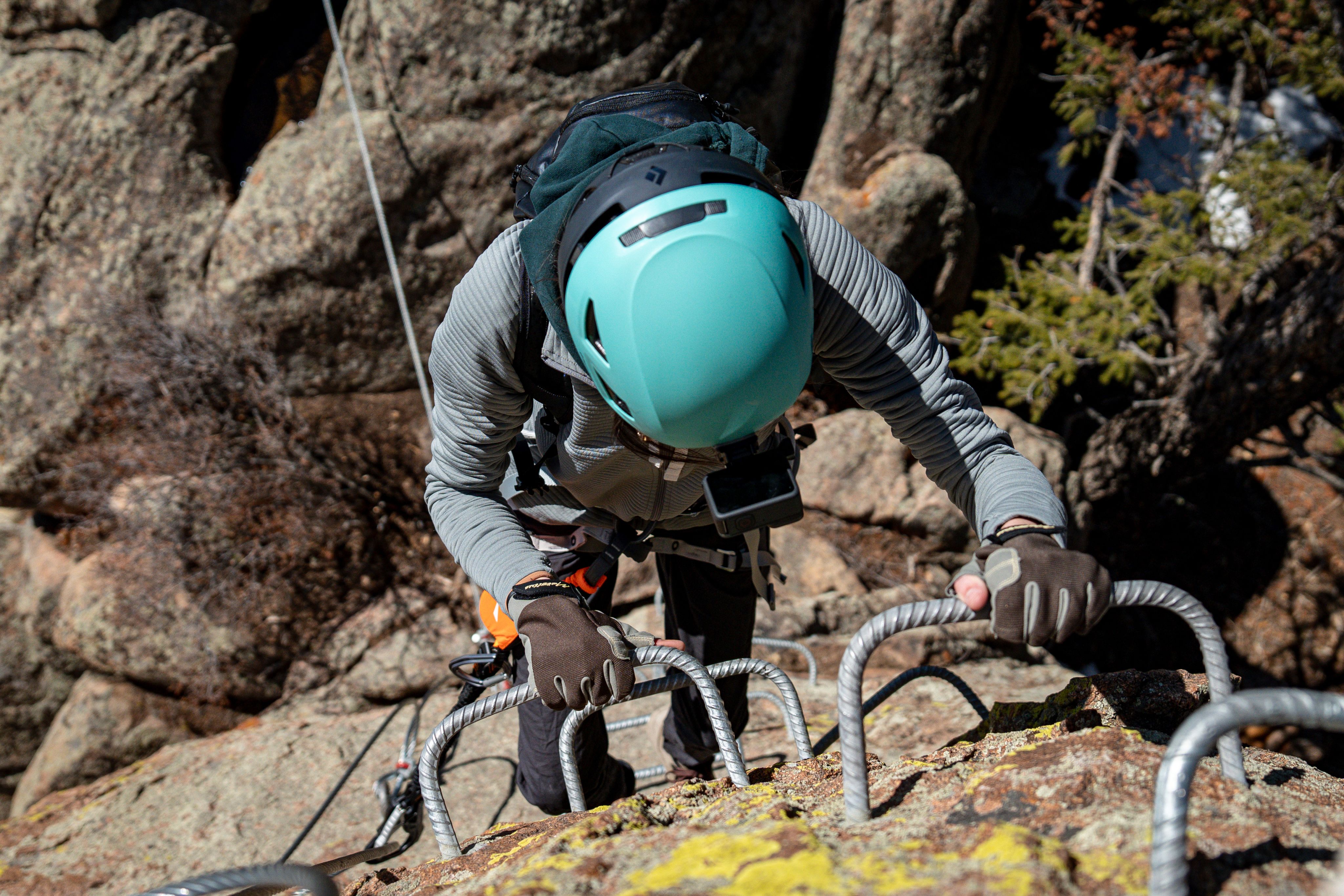A climber in a blue helmet ascends manmade holds at the Kennedy Mountain Campus