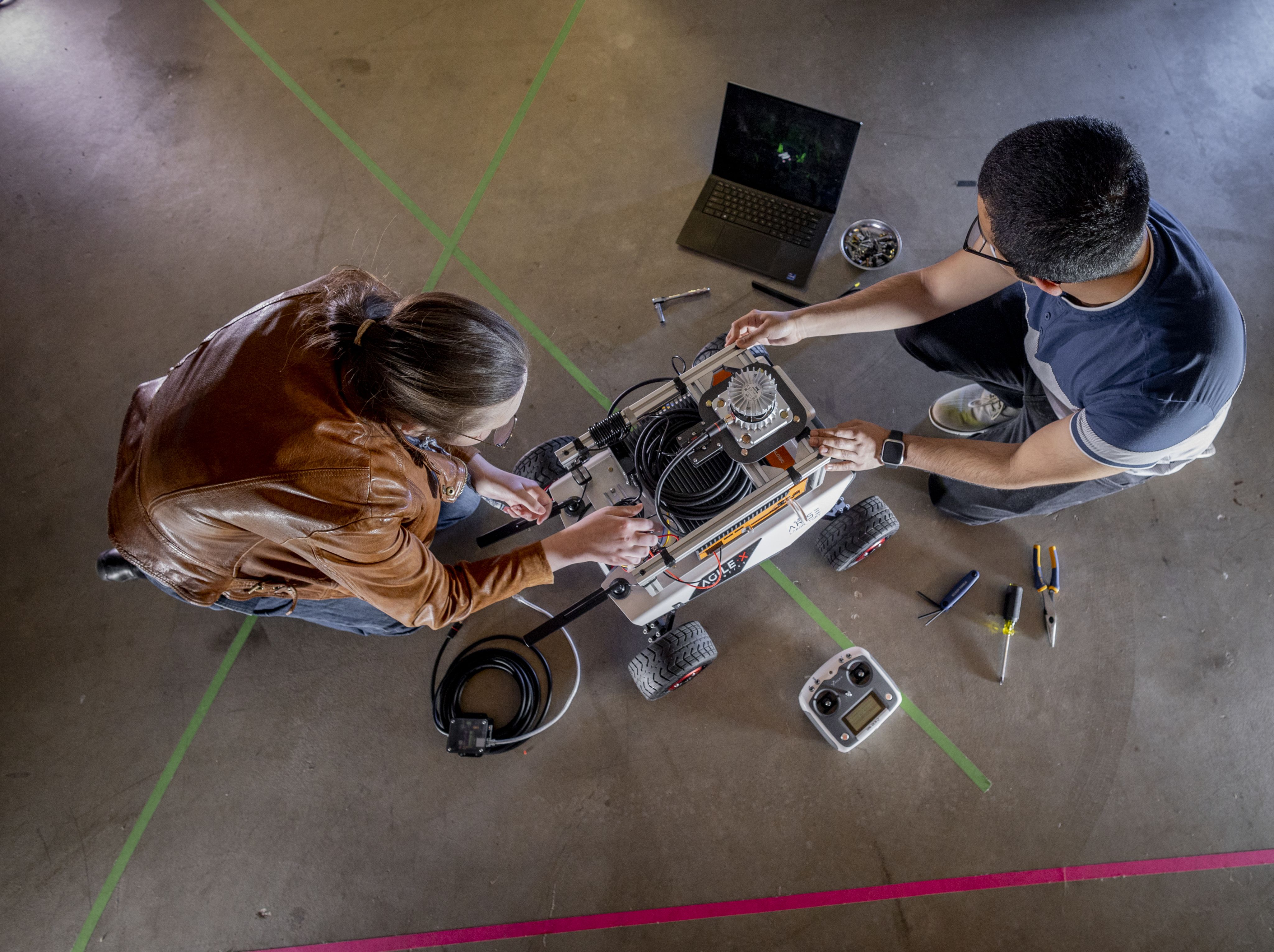 A view above of graduate student researchers working on a robotics project.