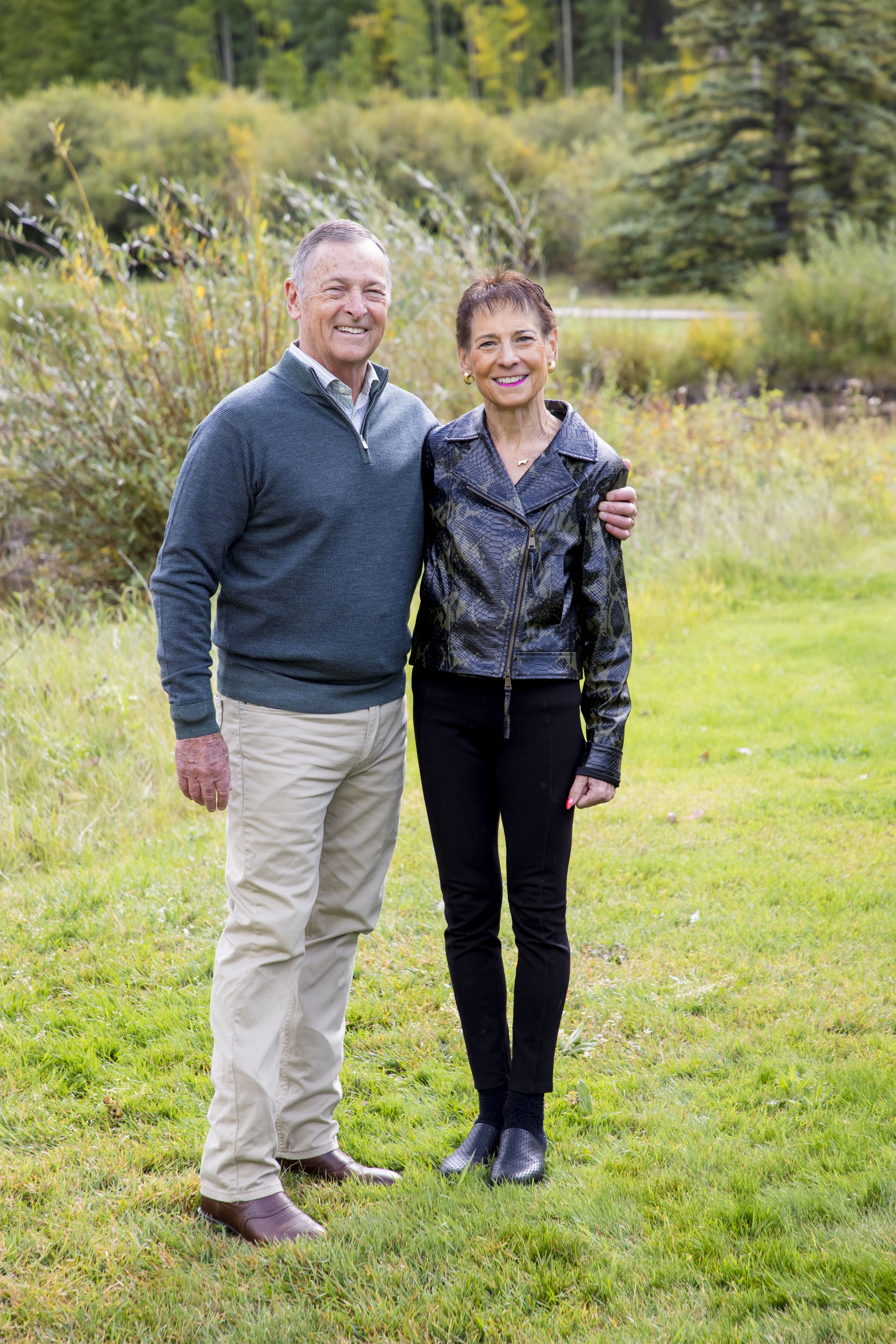Two people standing next to each other in a field, both of them smiling.