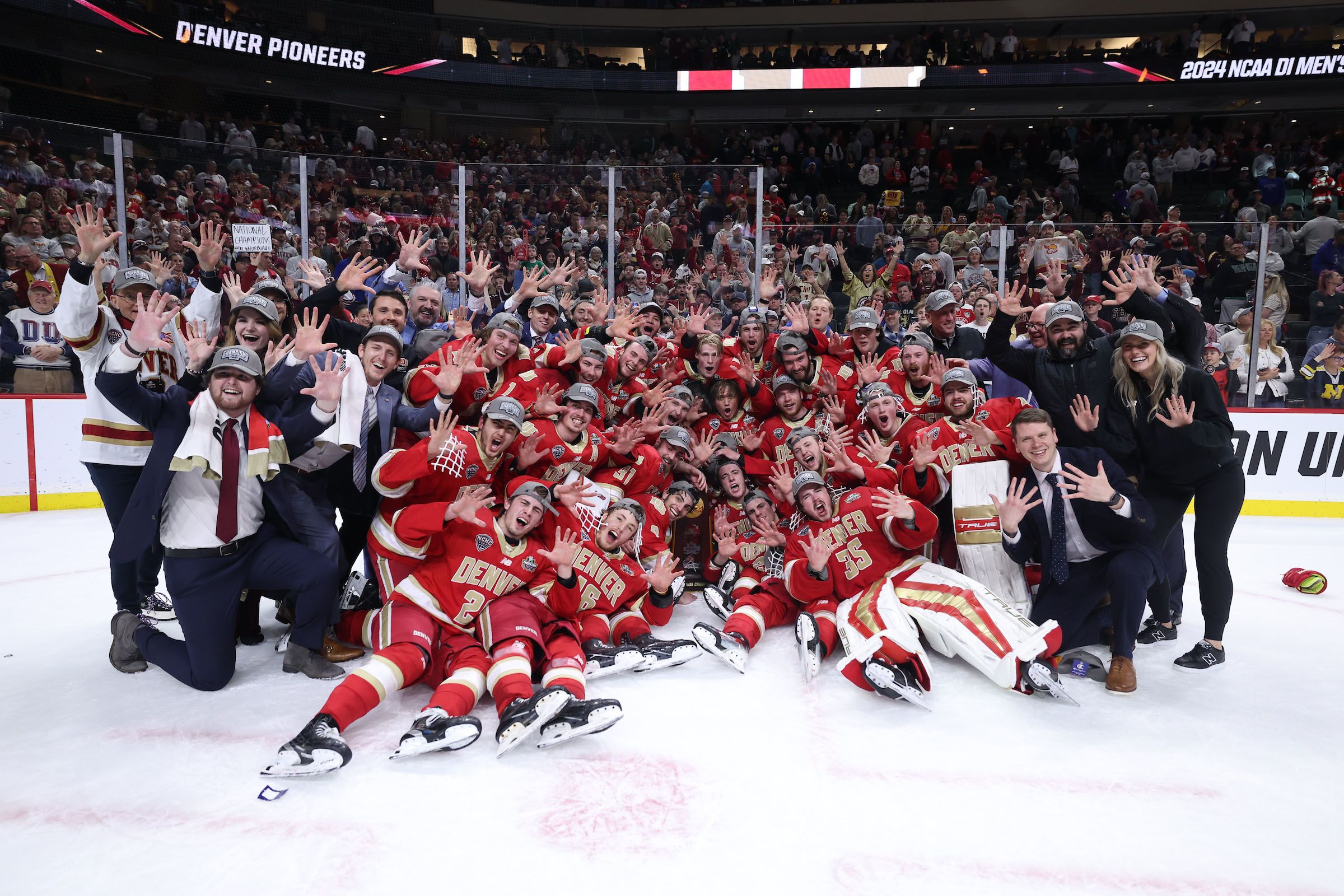 The University of Denver Men's Hockey Team holds up 10 fingers on the ice in front of the NCAA championship trophy.
