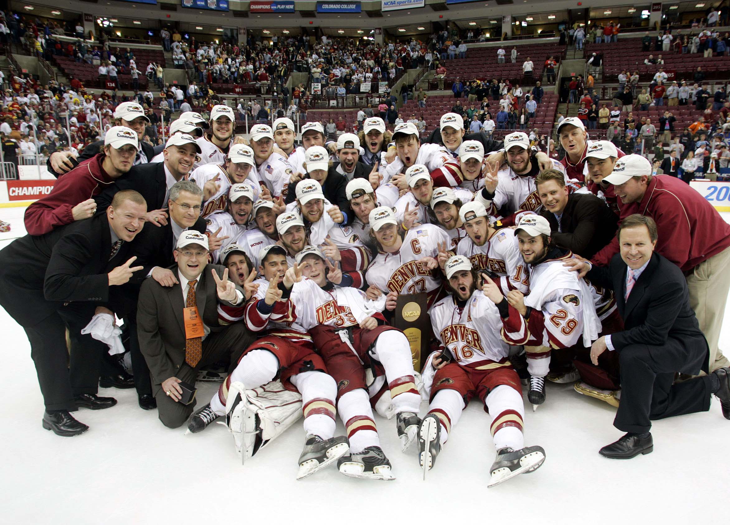 The 2005 University of Denver hockey team gathers in a group on the ice with the NCAA trophy.