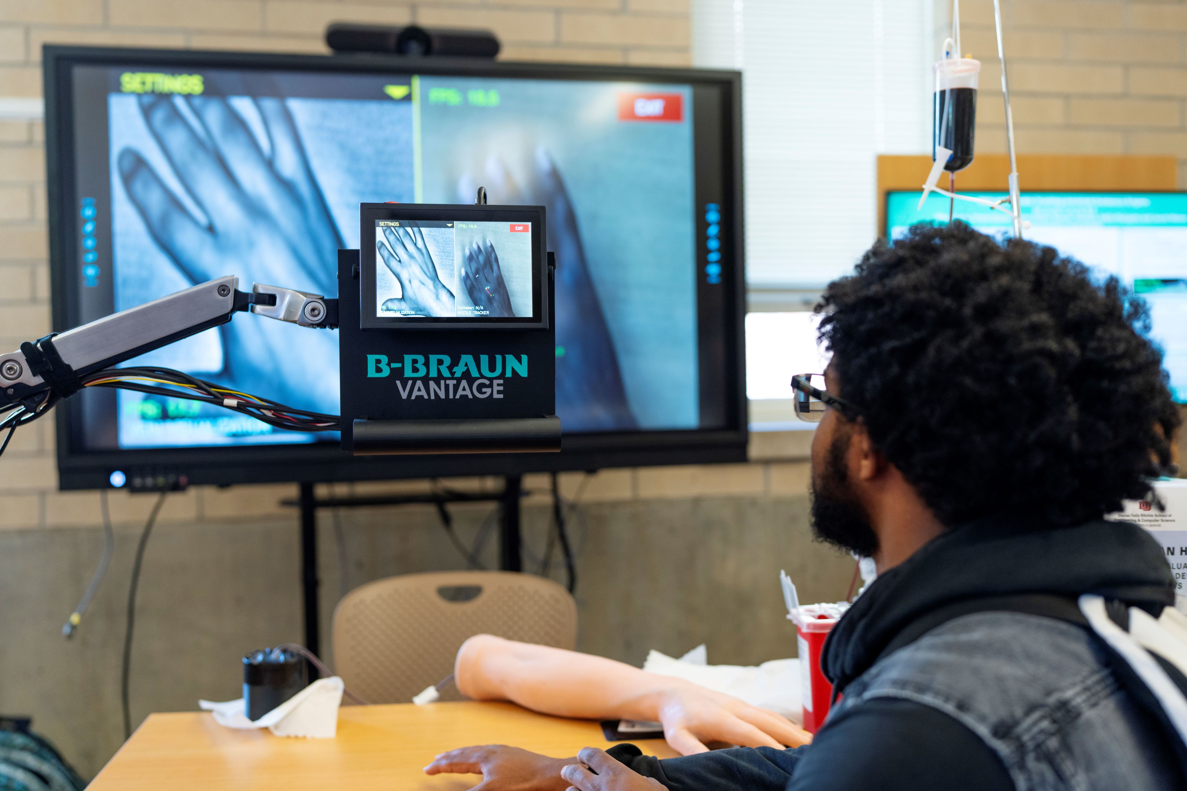 A student using a vein viewing device at the Senior Design Symposium