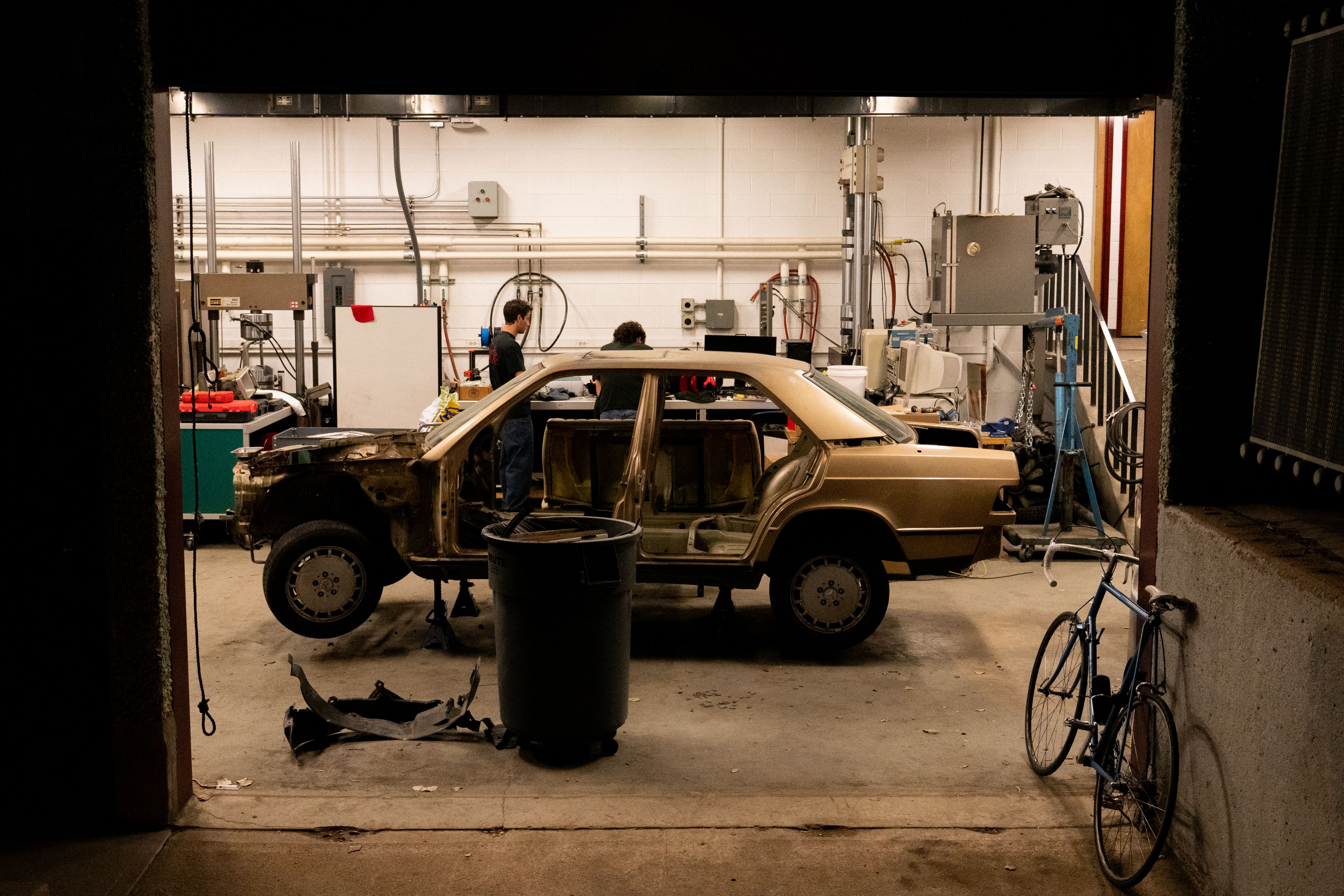 An old BMW on jacks in a garage at night
