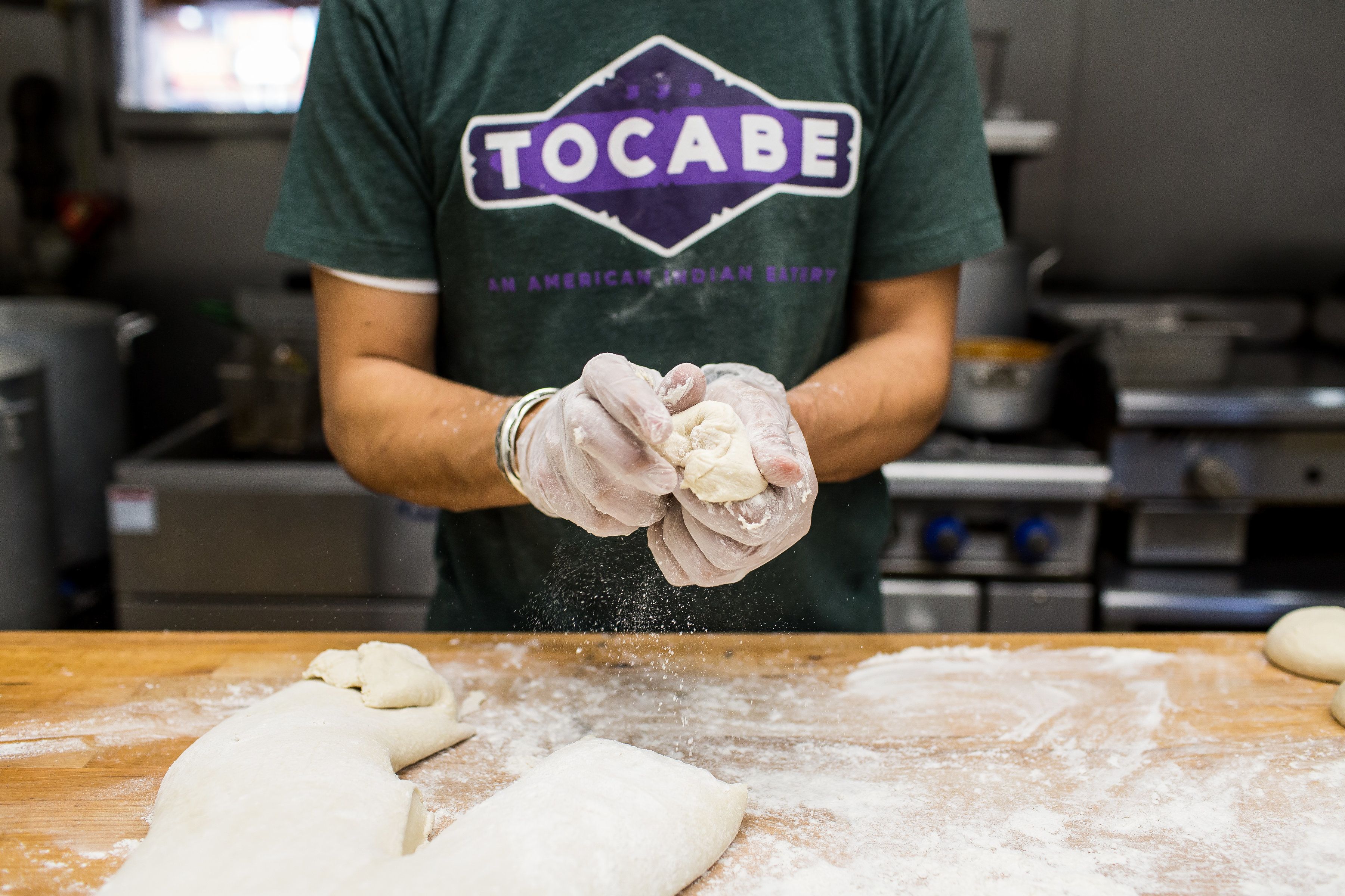 A cook wears a shirt with the name "Tocabe" on it. 