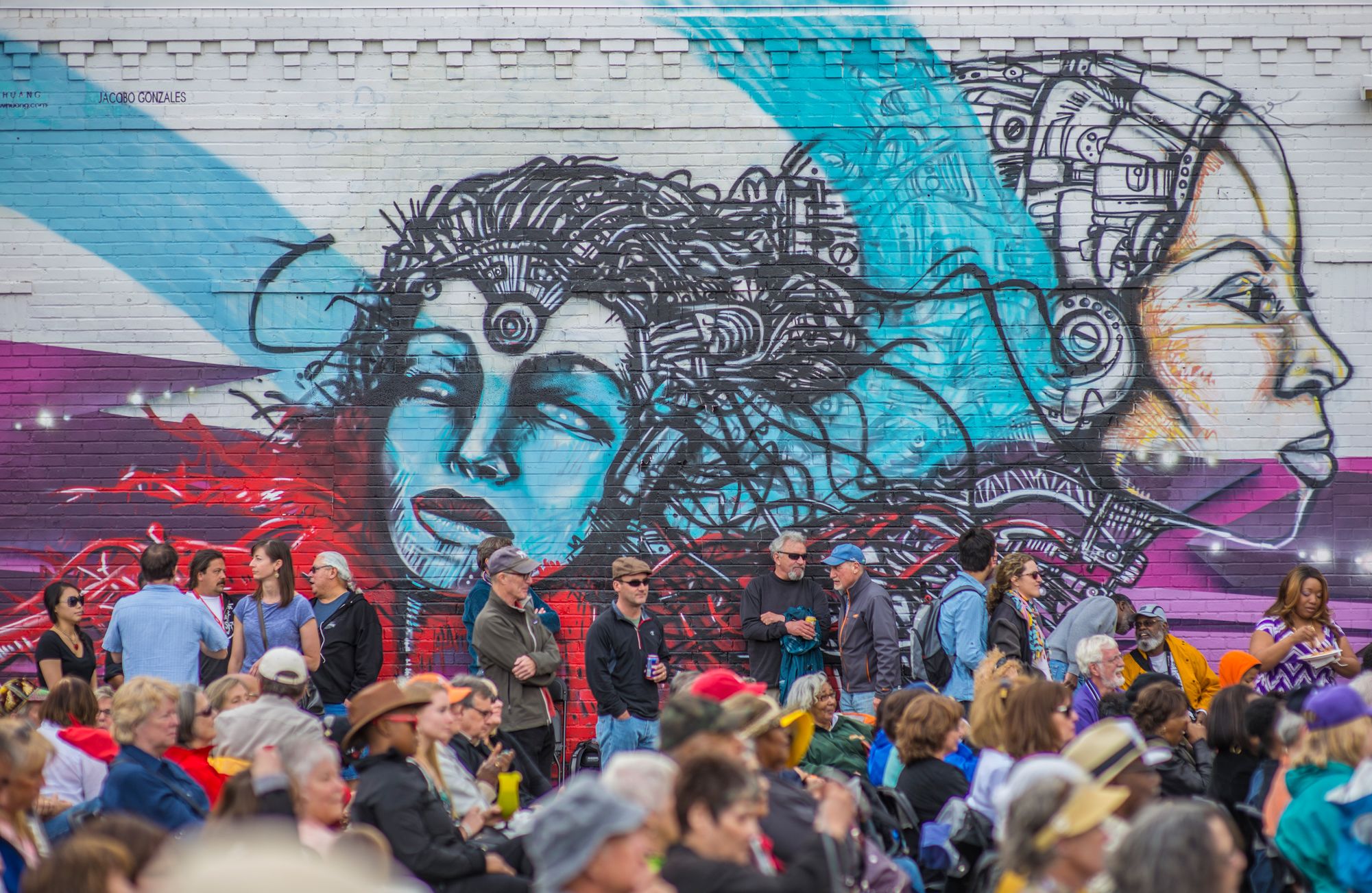 A crowed at the Five Points Jazz Festival, with a purple and blue mural in the background