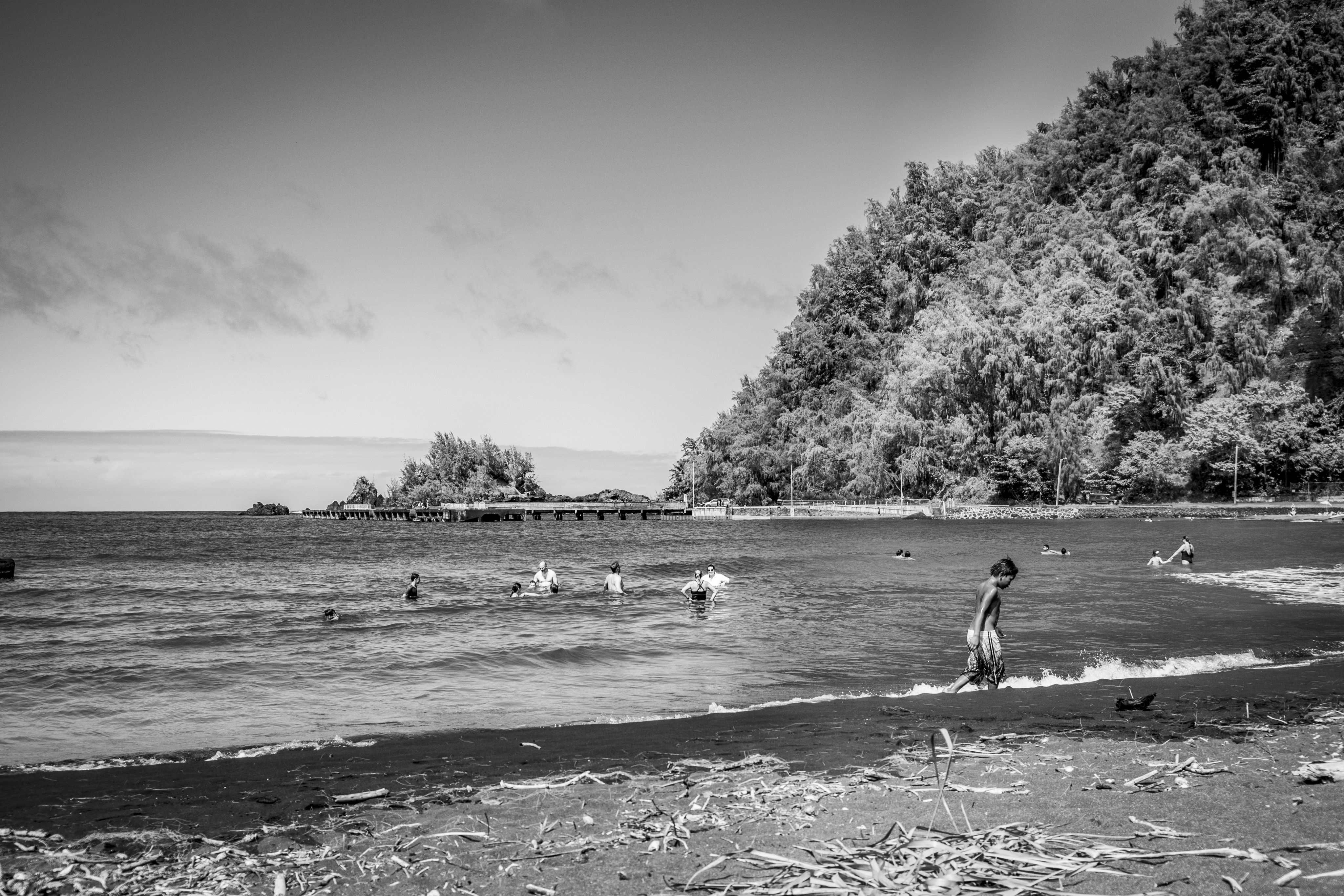 Children and adults play in the water at a beach.