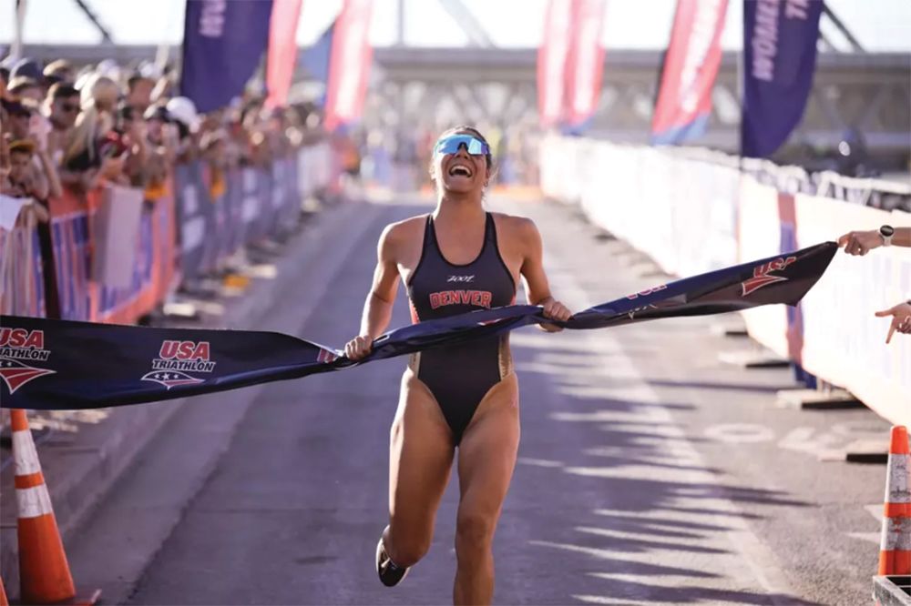 A triathlete crosses the first place finish line ribbon. 