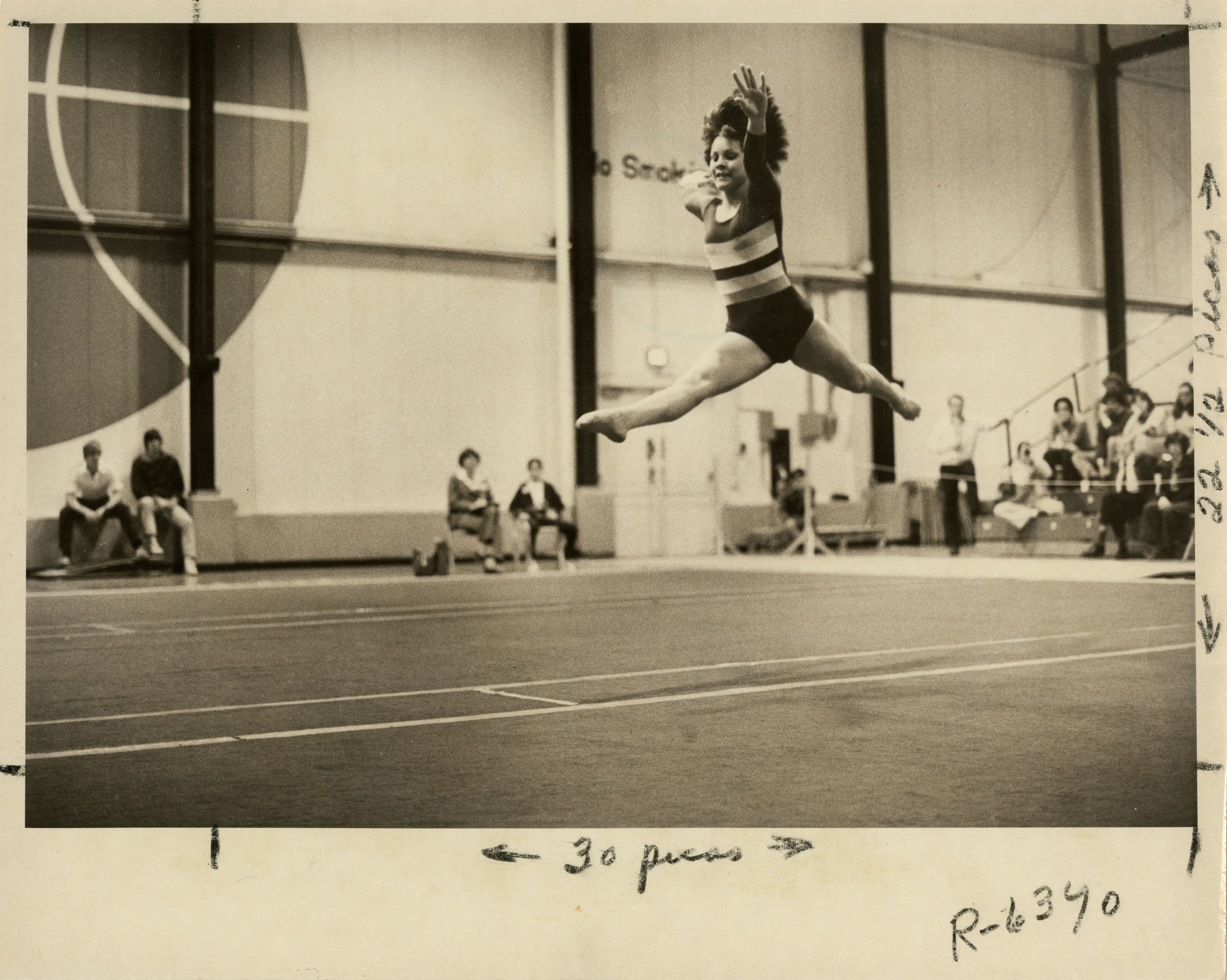 University of Denver (DU) Pioneers women's gymnastics team member jumps in the air and performs the splits during a floor routine at a meet.