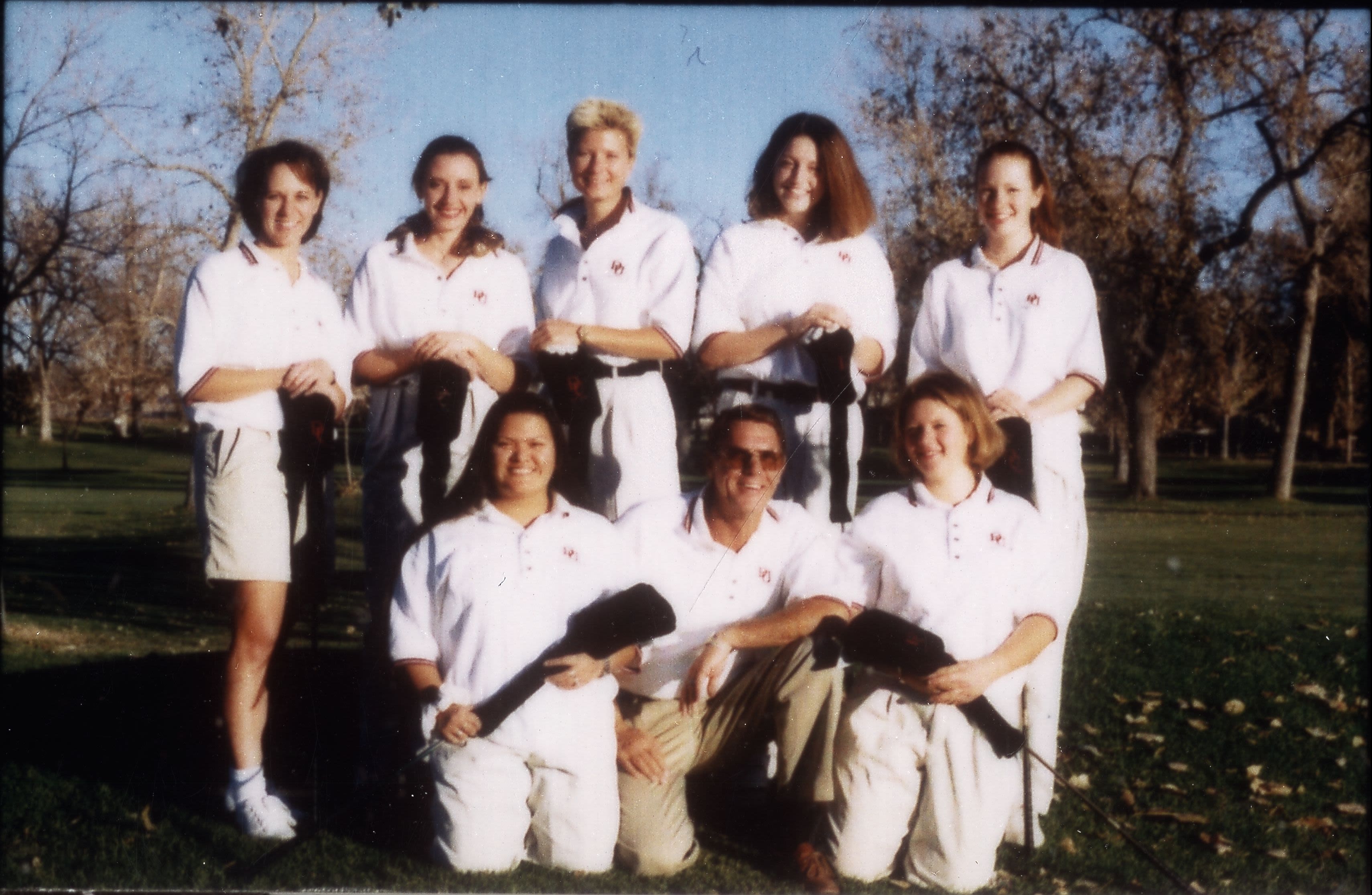 The University of Denver (DU) Pioneers women's golf team and coach pose for a group portrait outdoors.
