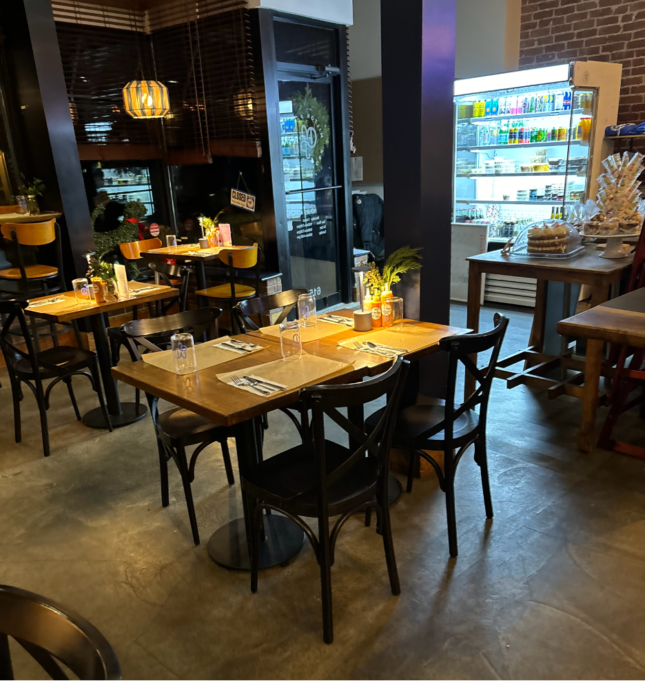A table inside Milton Point Provisions. A drink cooler is visible in the background. The windows behind the table show that it is night time.