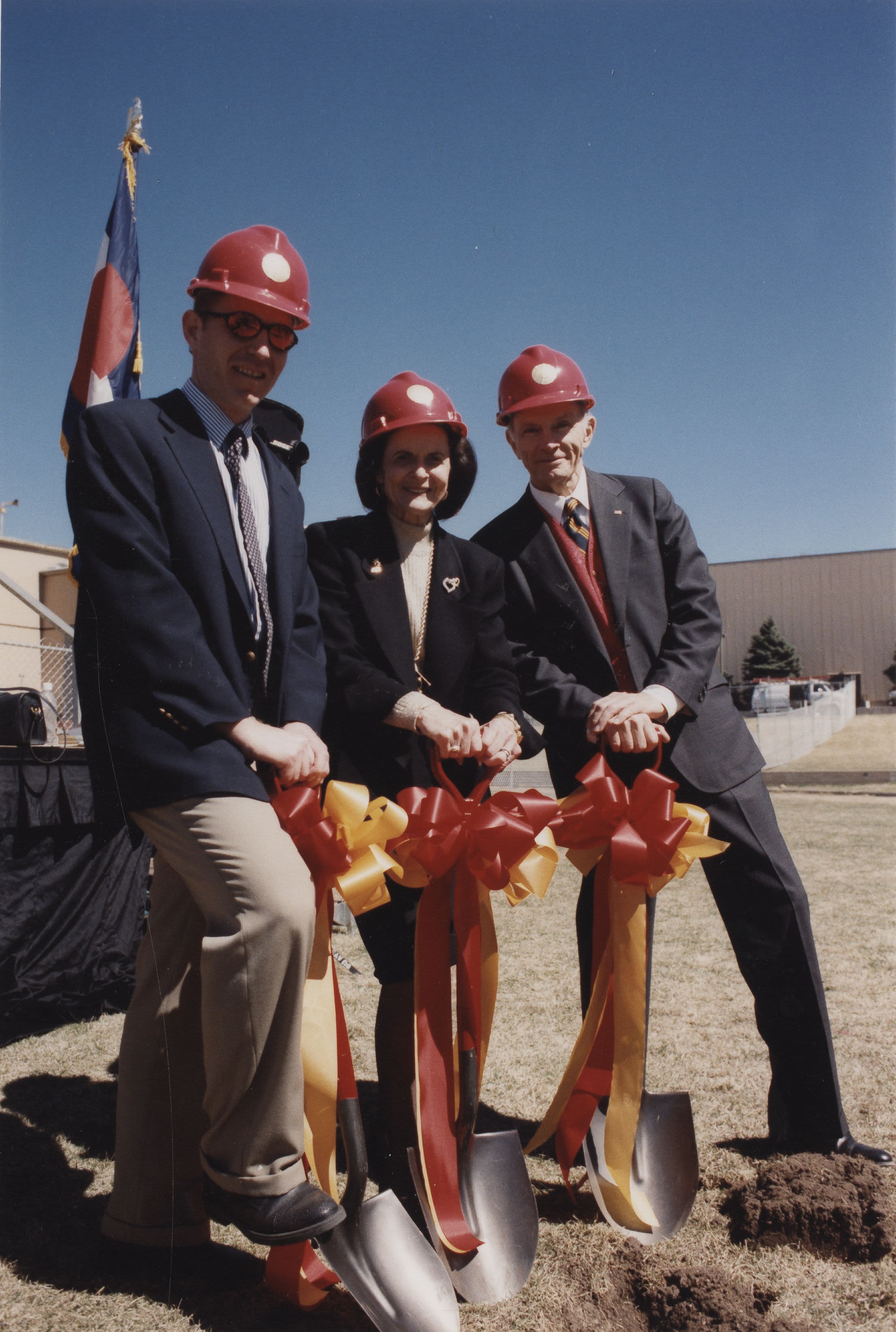 Three people in dress attire breaking ground
