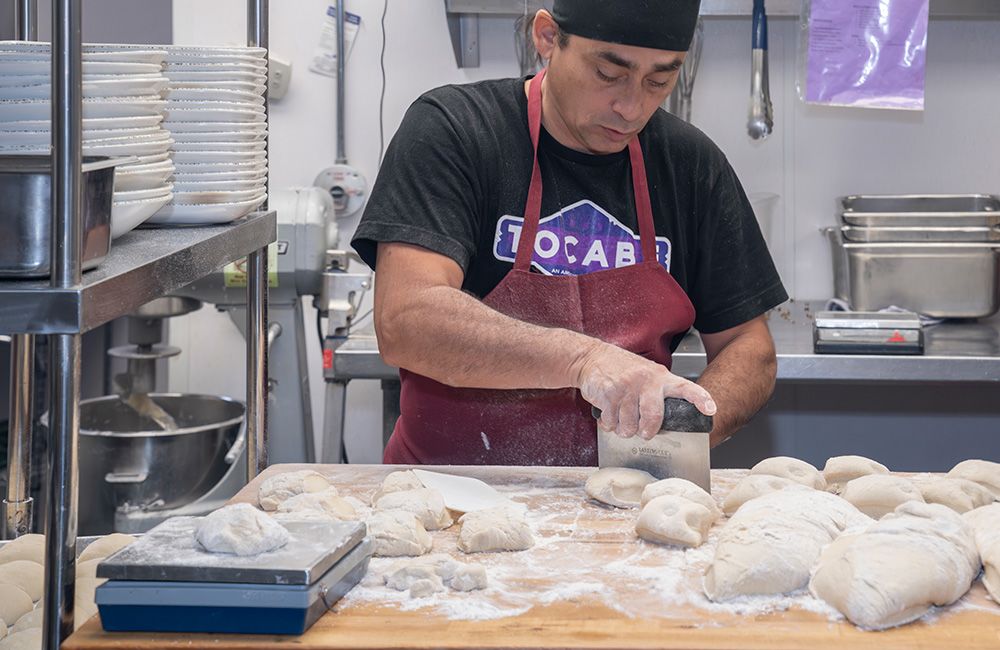 A cook at Tocabe cuts dough.