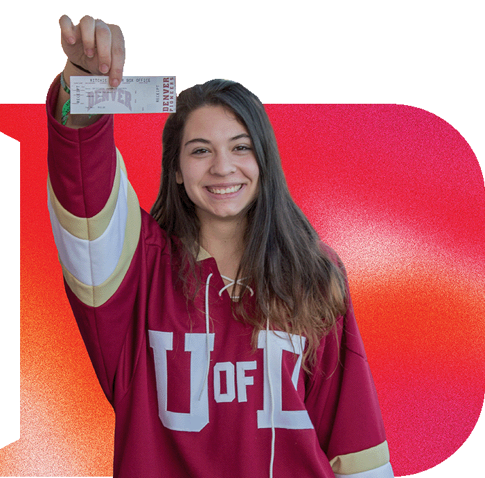 Graphic collage of a red-orange gradient letter "D" behind a photo of a female college student, wearing a "U of D" hockey jersey and smiling and she proudly holds up a hockey ticket.