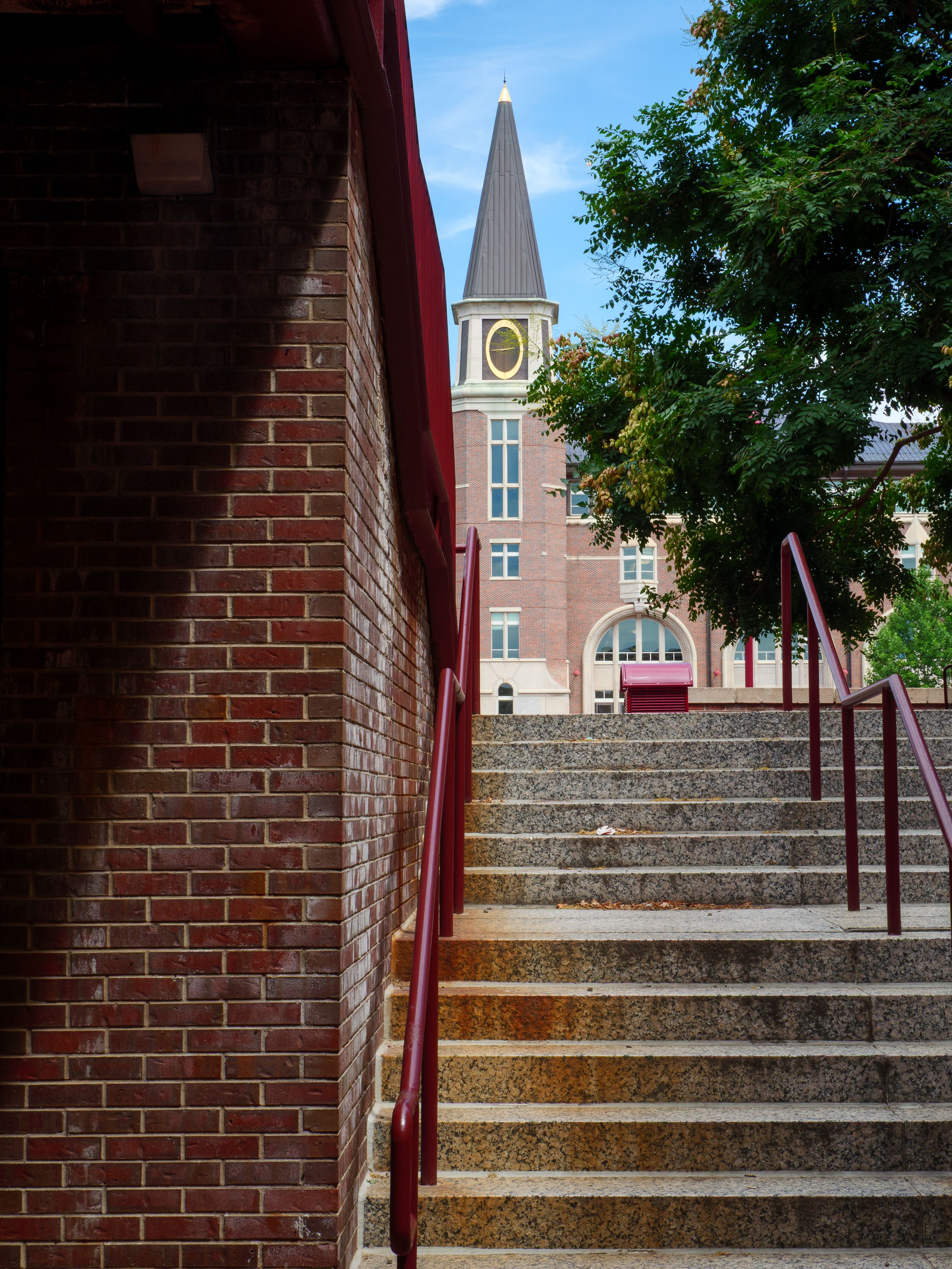 stairs with a brick building and clock tower in the background