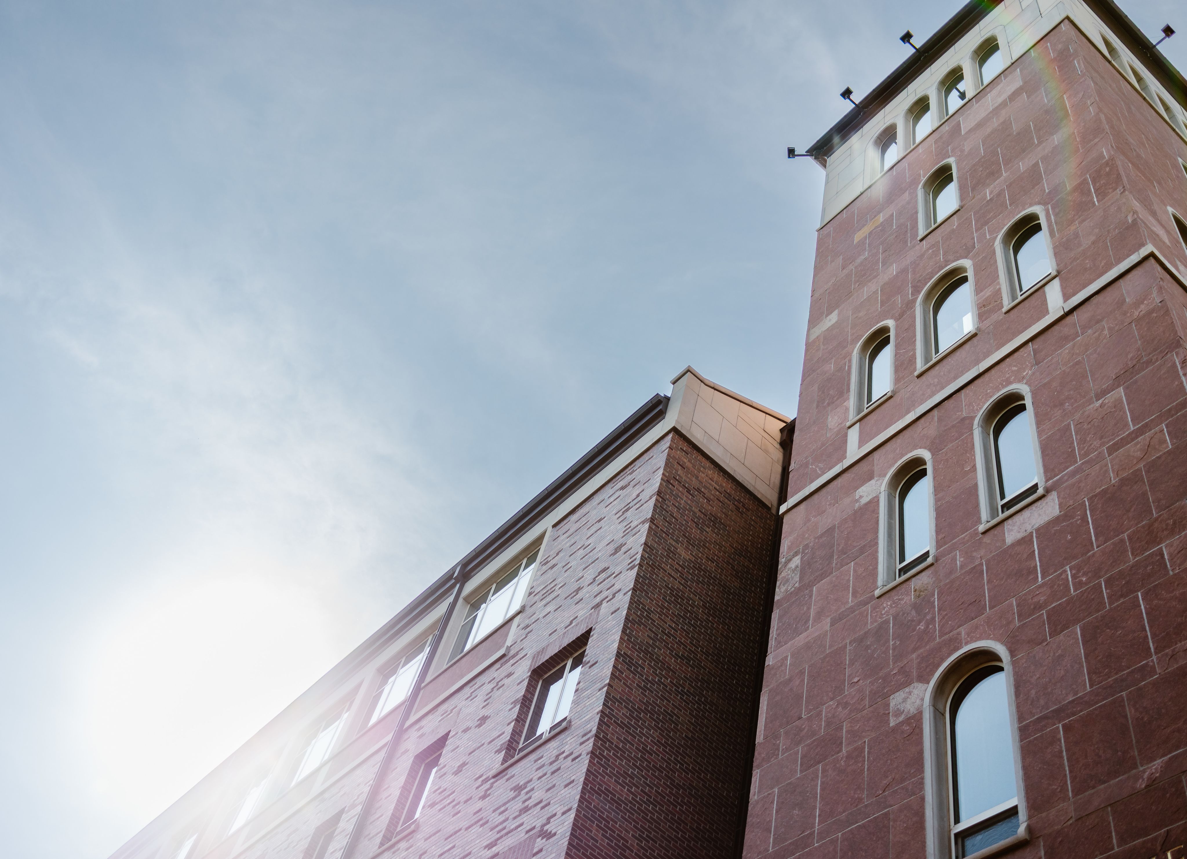 A brick bulding facade with pale blue sky in the background