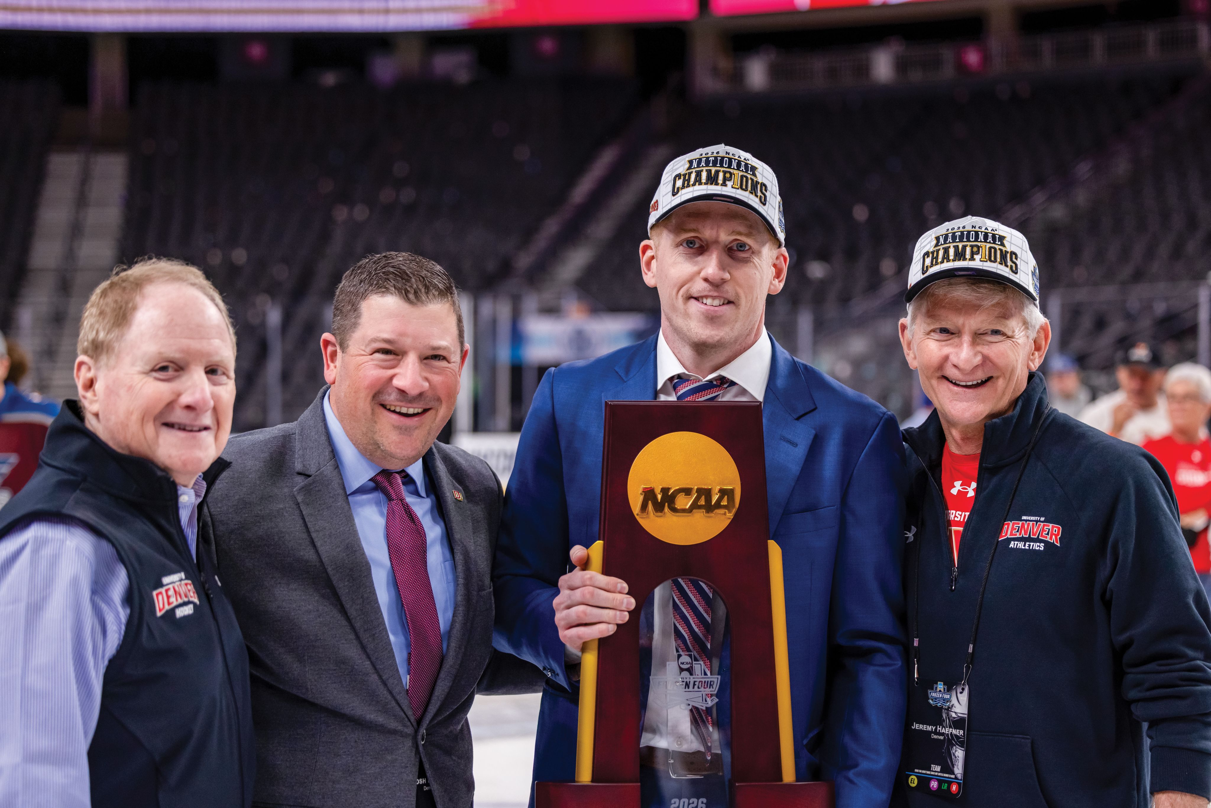 four men holding a NCAA trophy