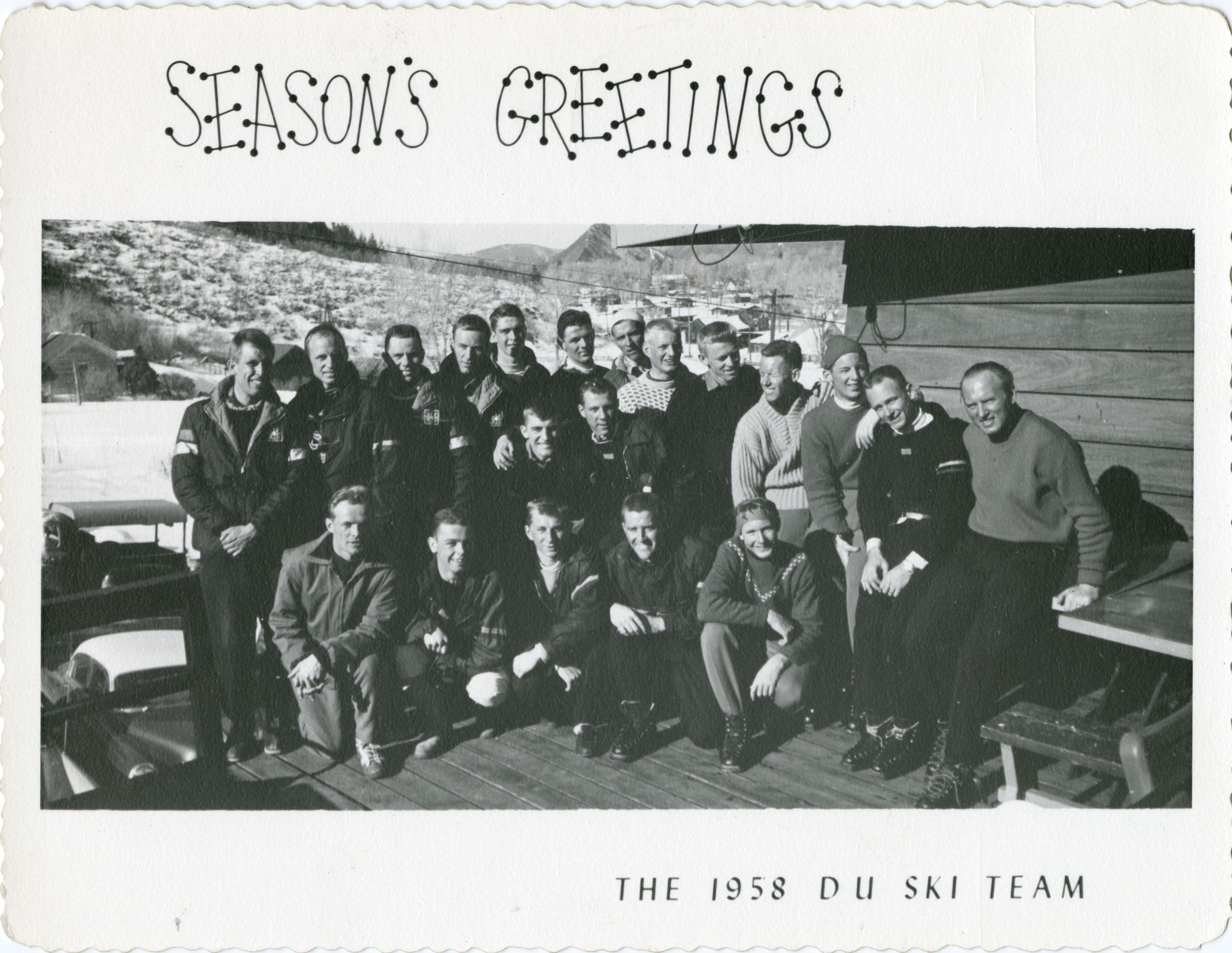 The ski team gathers on a patio of a wooden cabin in the mountains to pose for a photo.