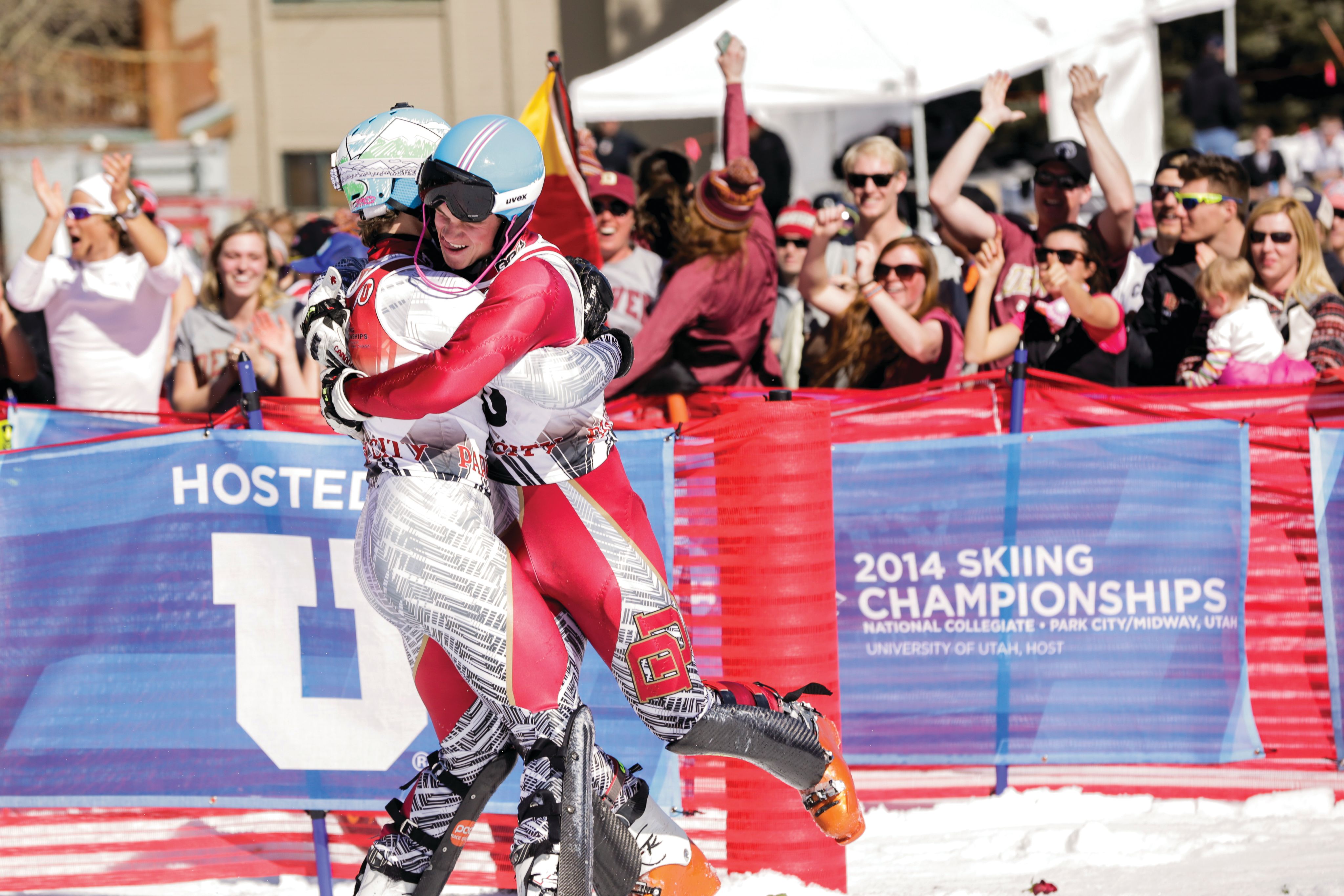 Lysdahl and Philip embrace in a hug in their racing uniforms in the race finish area as the crowd cheers behind them.