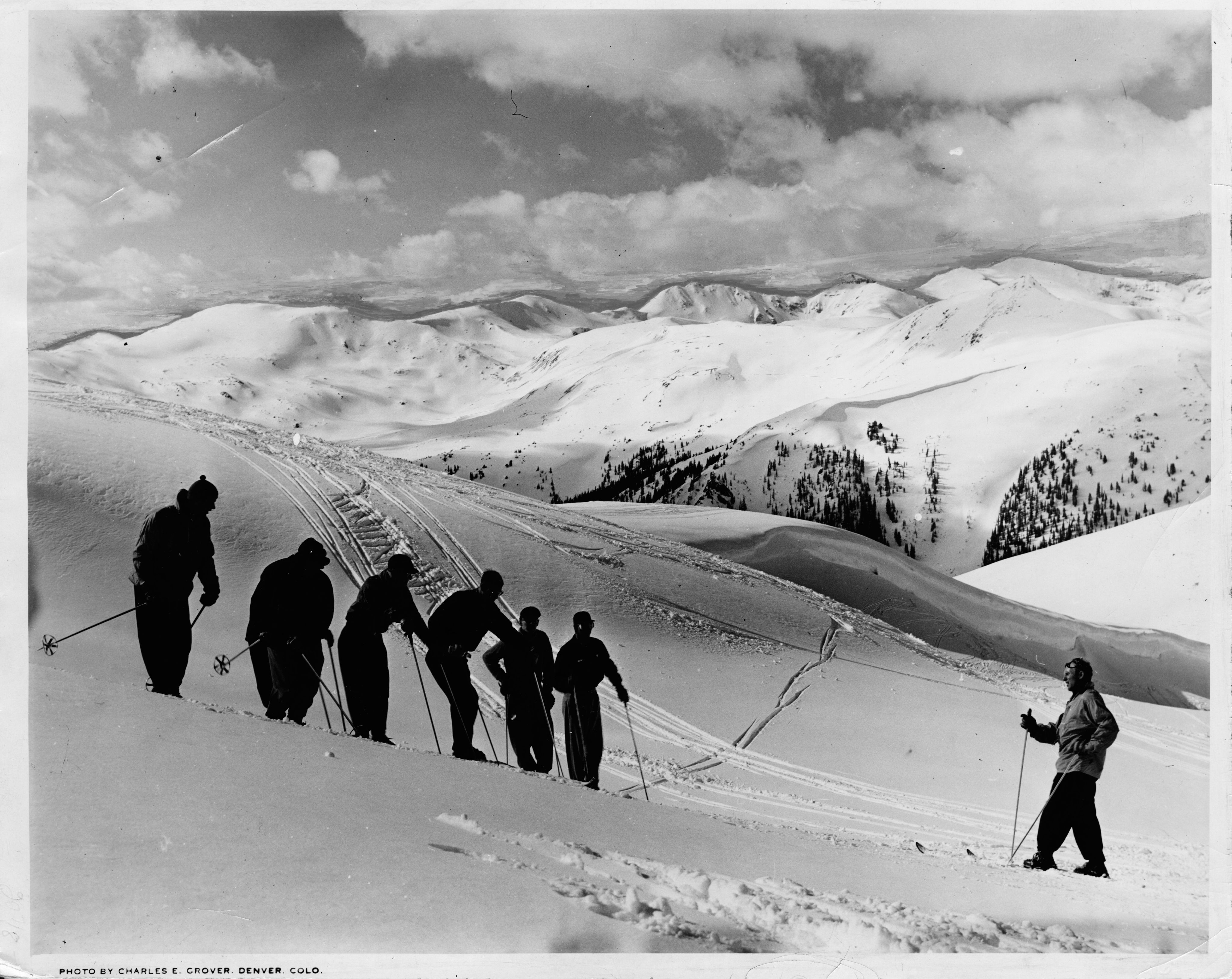 Skiers practicing on hill with Willy Shaeffler and mountains in the background 