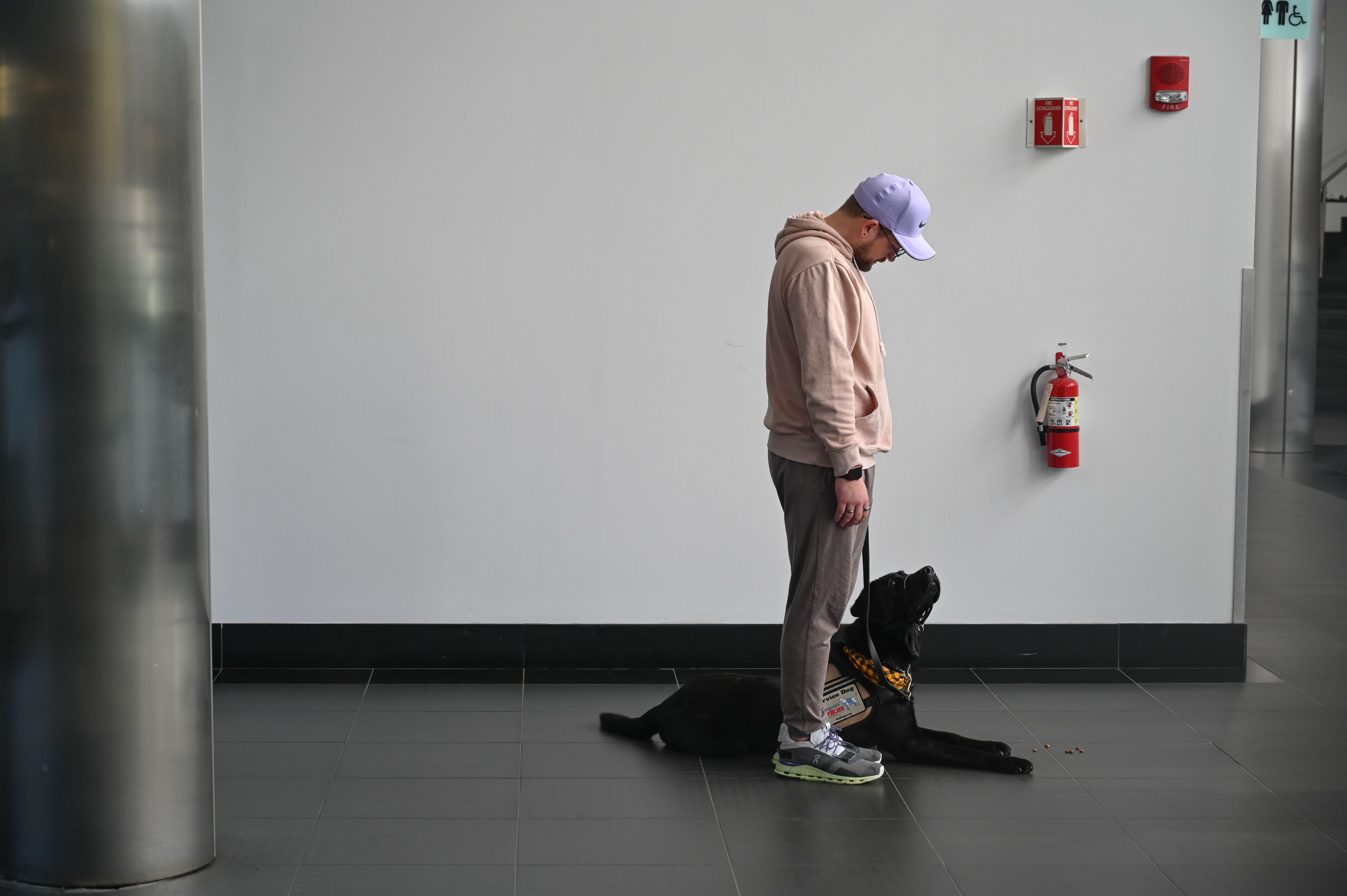 A man standing while his service dog lays at his feet
