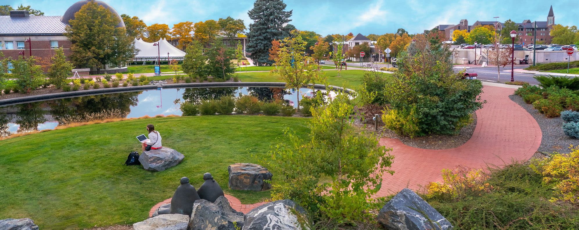 A photo of Dan's Garden, with a student studying while sitting on a rock