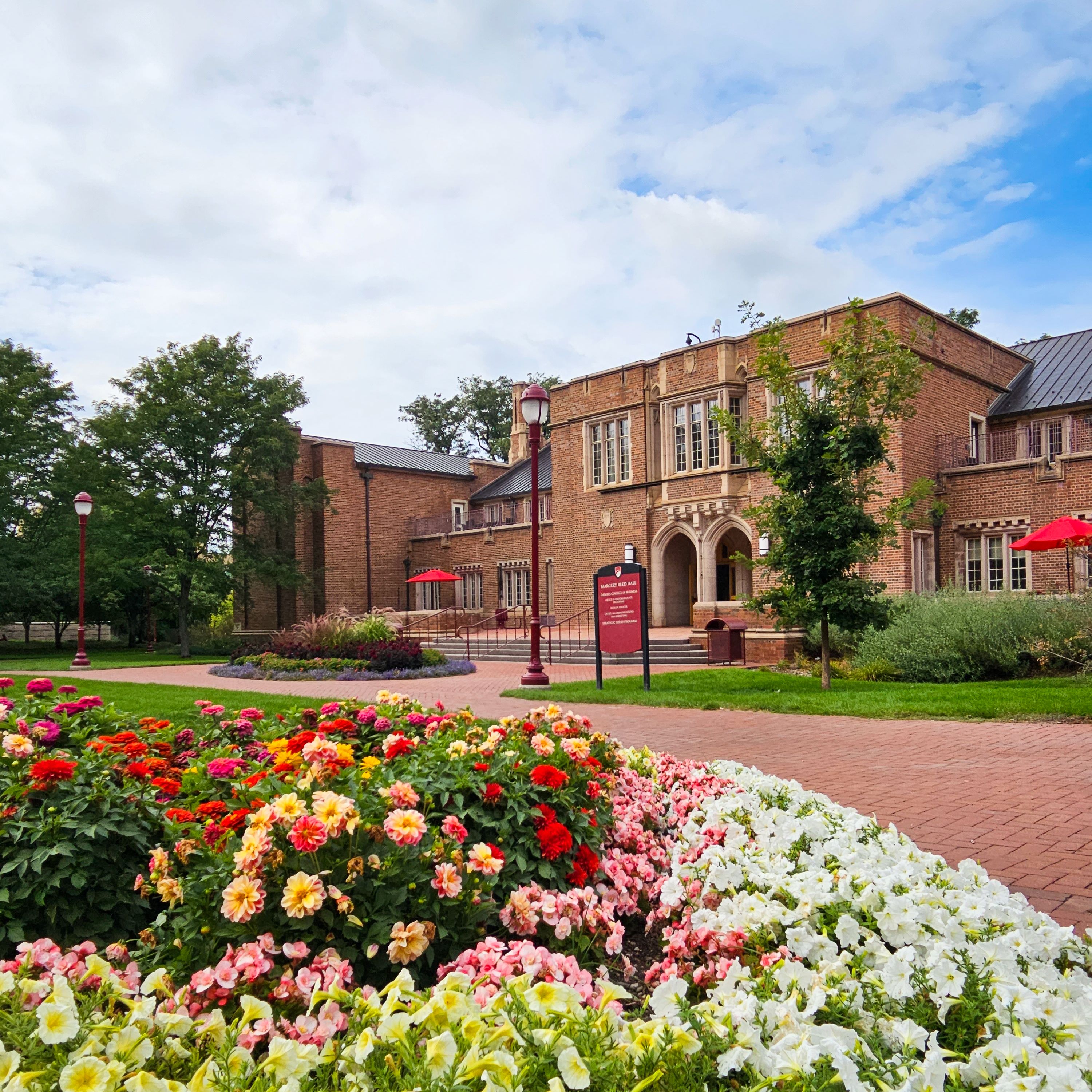 A photo of the exterior of Margery Reed Hall with flowers visible in the foreground