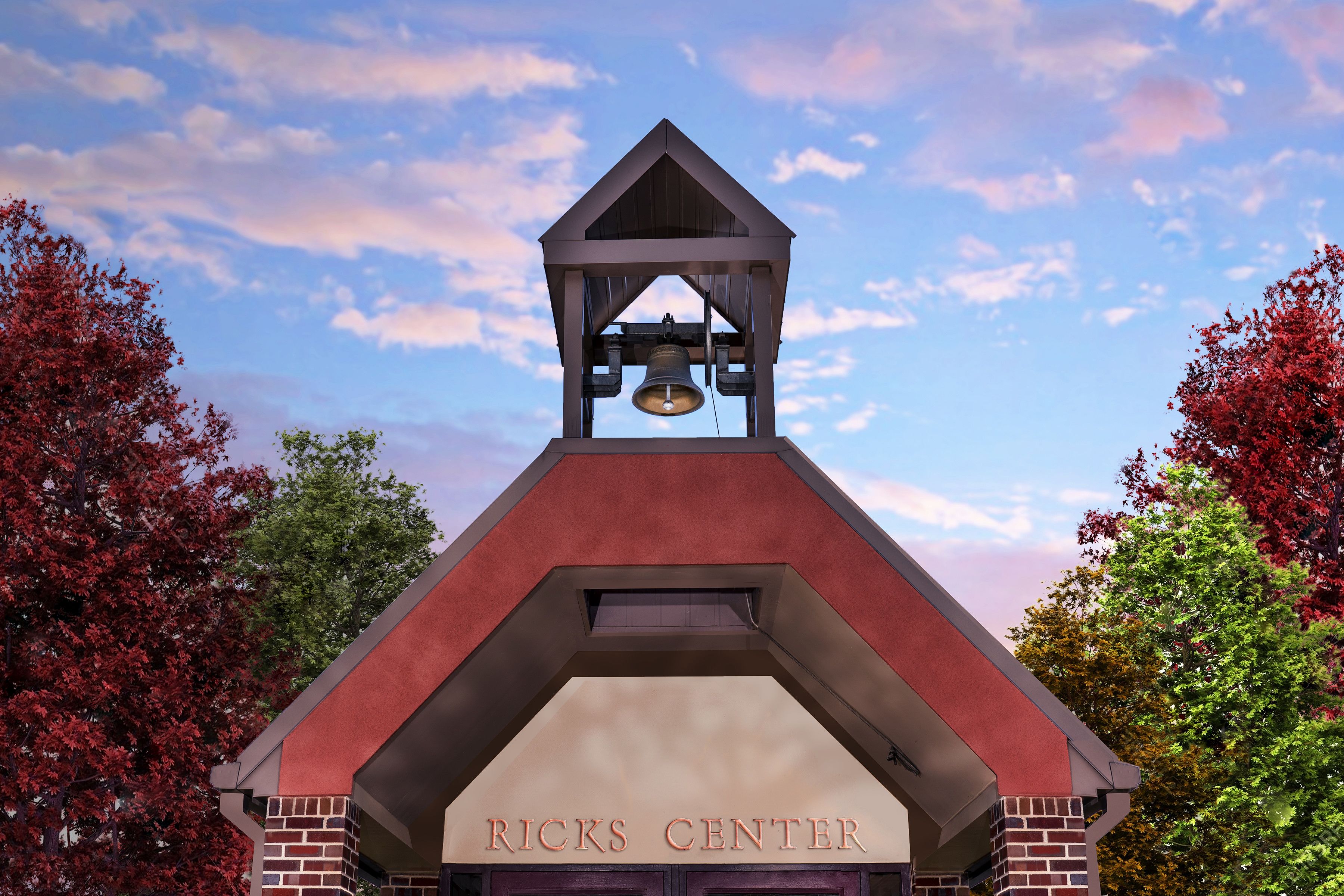 A sunset photo of the bell above the entrance to the Ricks Center