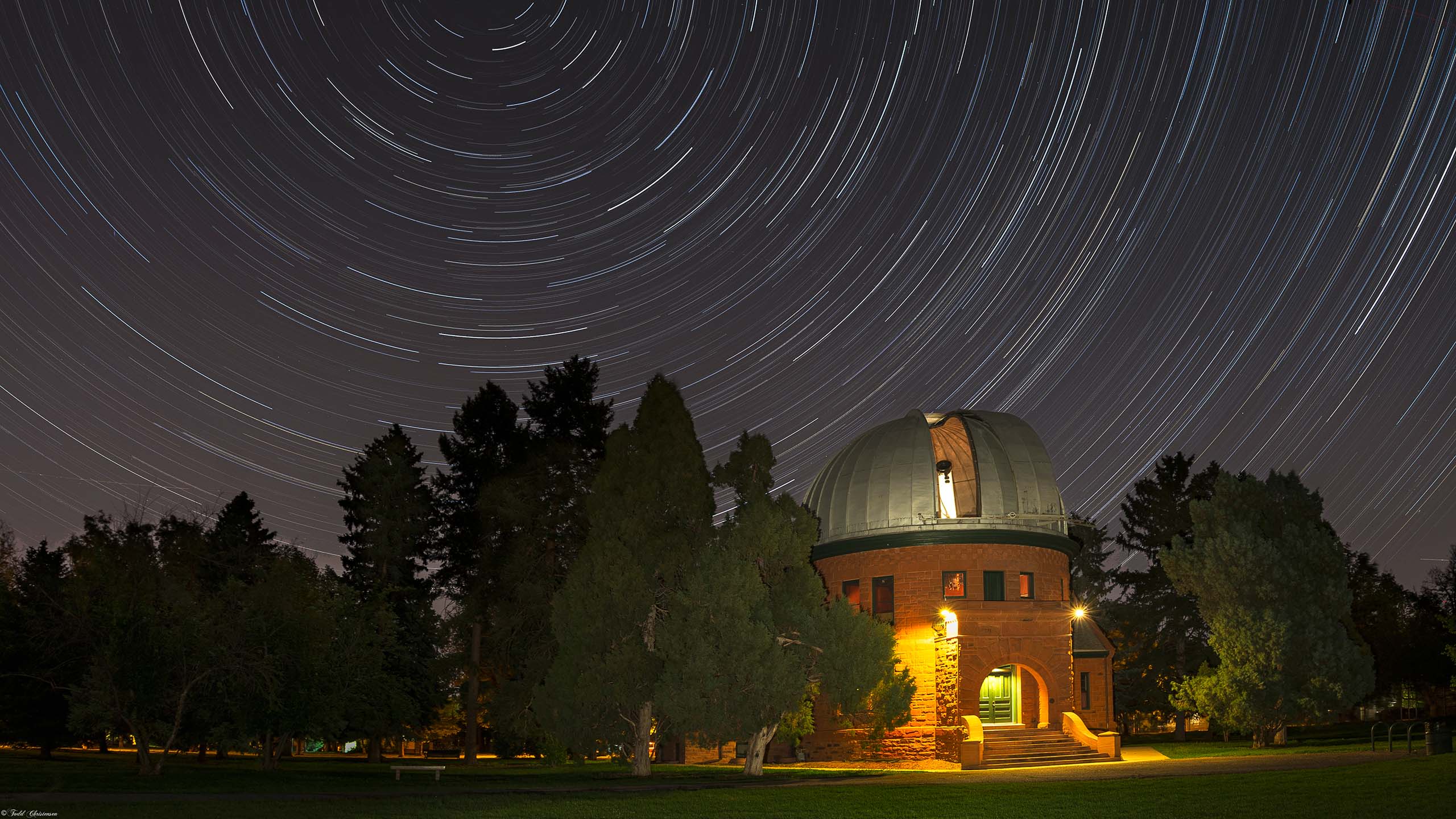 A long exposure shot of the Chamberlin Observatory at night, with stars swirling in the night sky.