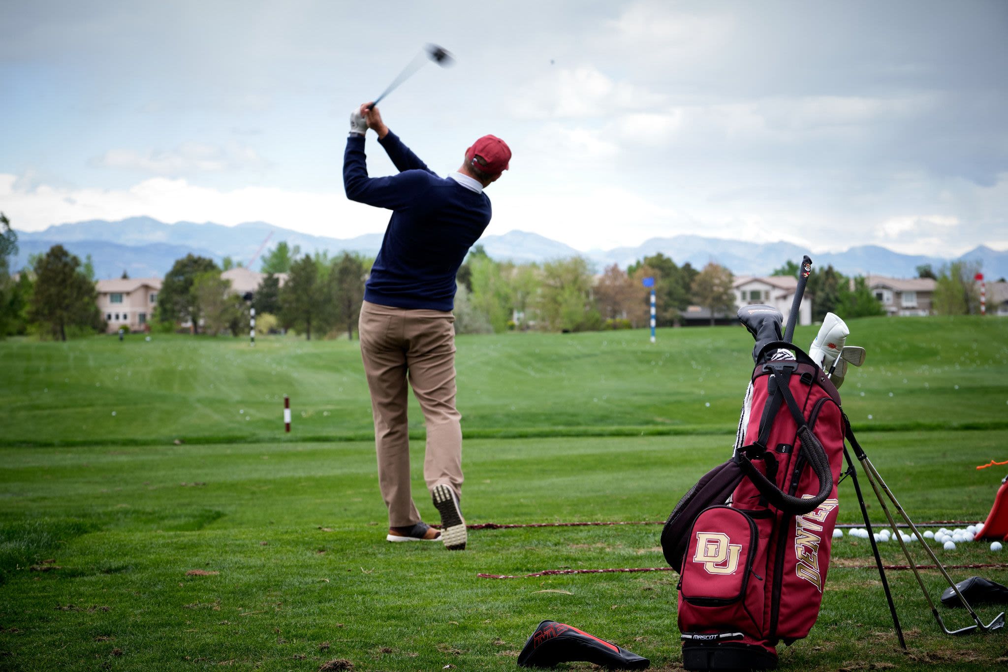 A golfer hits a ball facing the mountains at the DU Alumni Golf tournament.