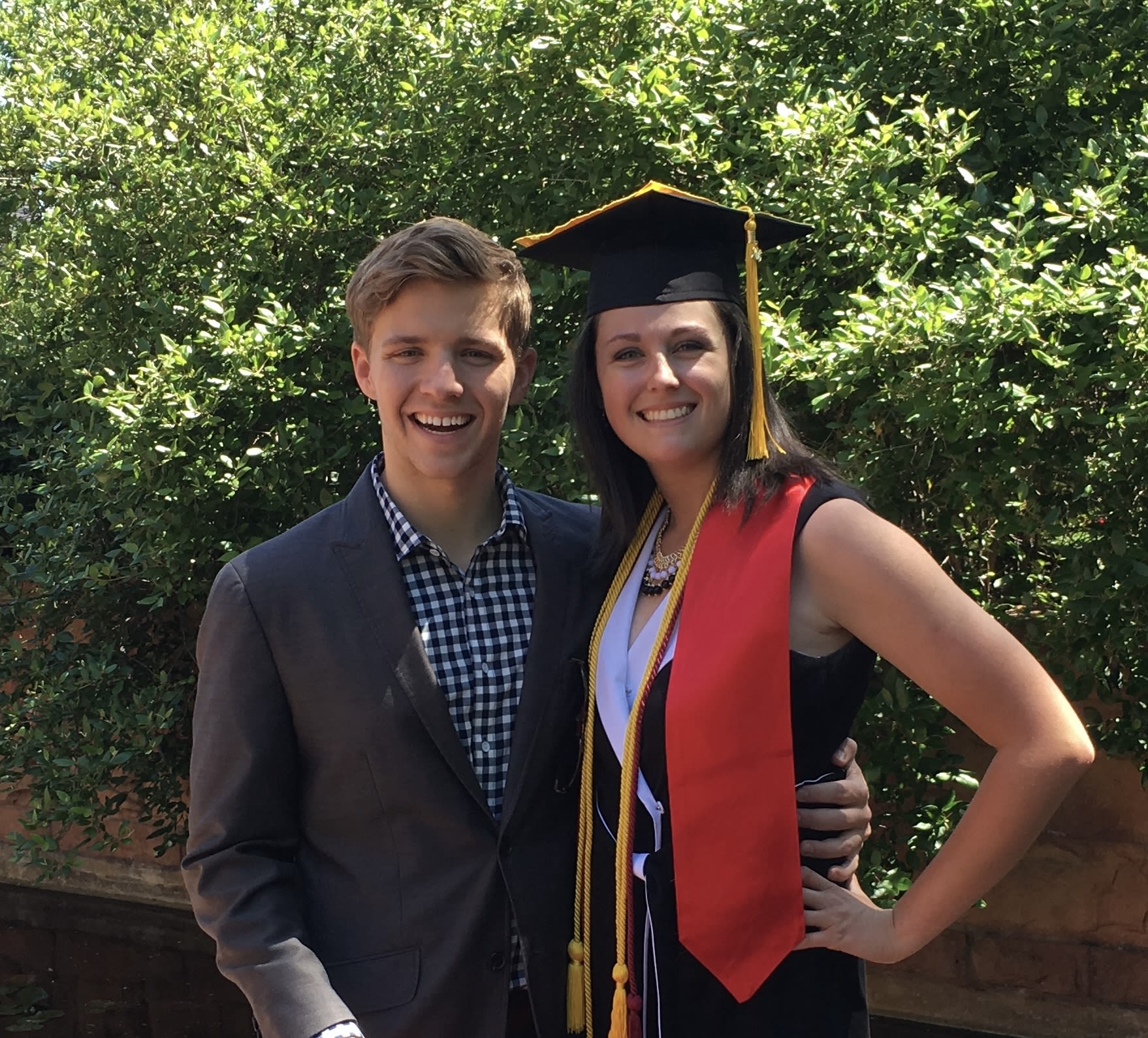 Amanda stands with her husband Jack on campus in a graduation cap