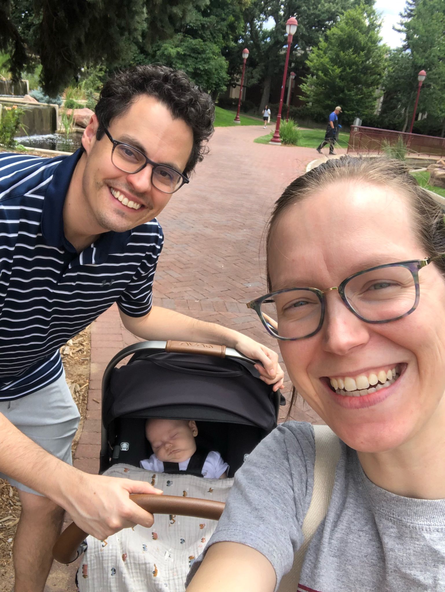 Parents take a selfie on the DU campus with the newborn baby in a stroller behind them