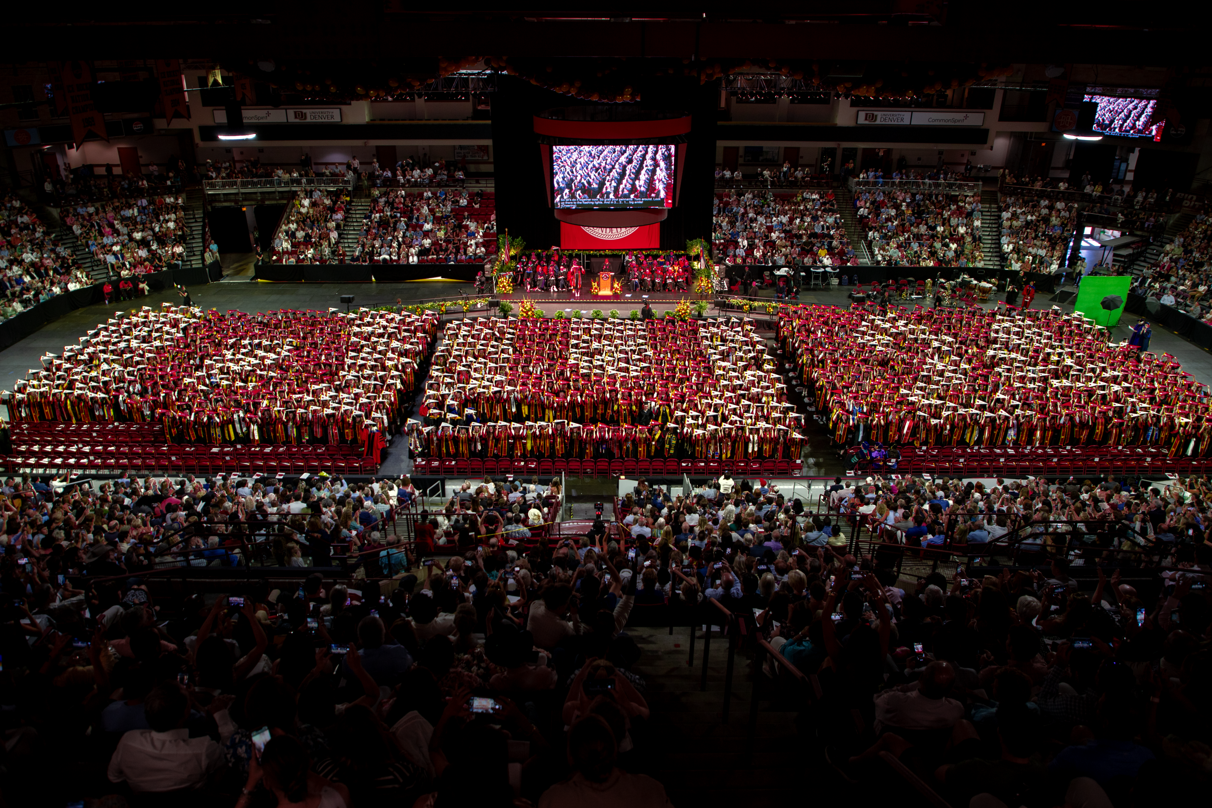 DU's class of 2024 holds red and white pennants above their heads, spelling out "DU 24"