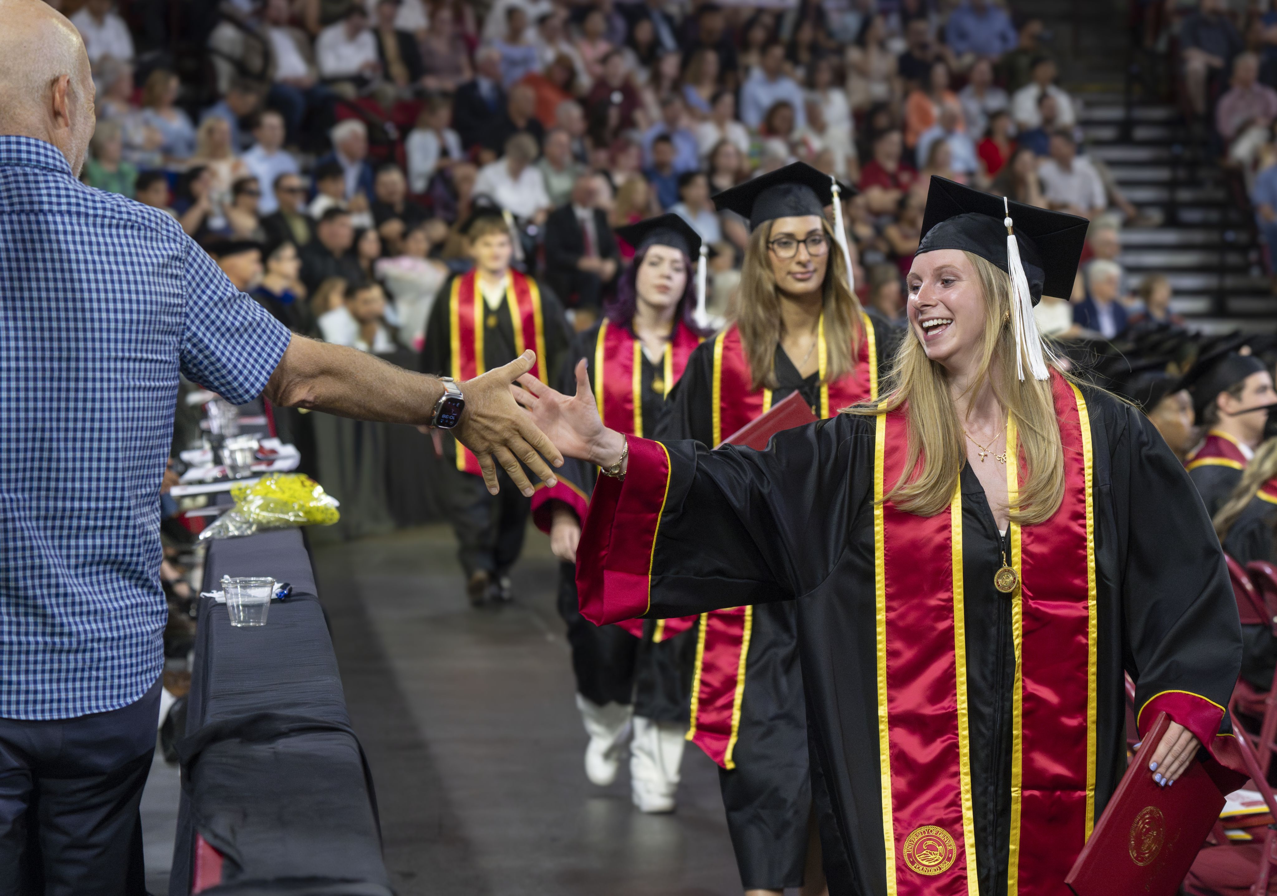 A line of students high-fiving members of the audience at commencement
