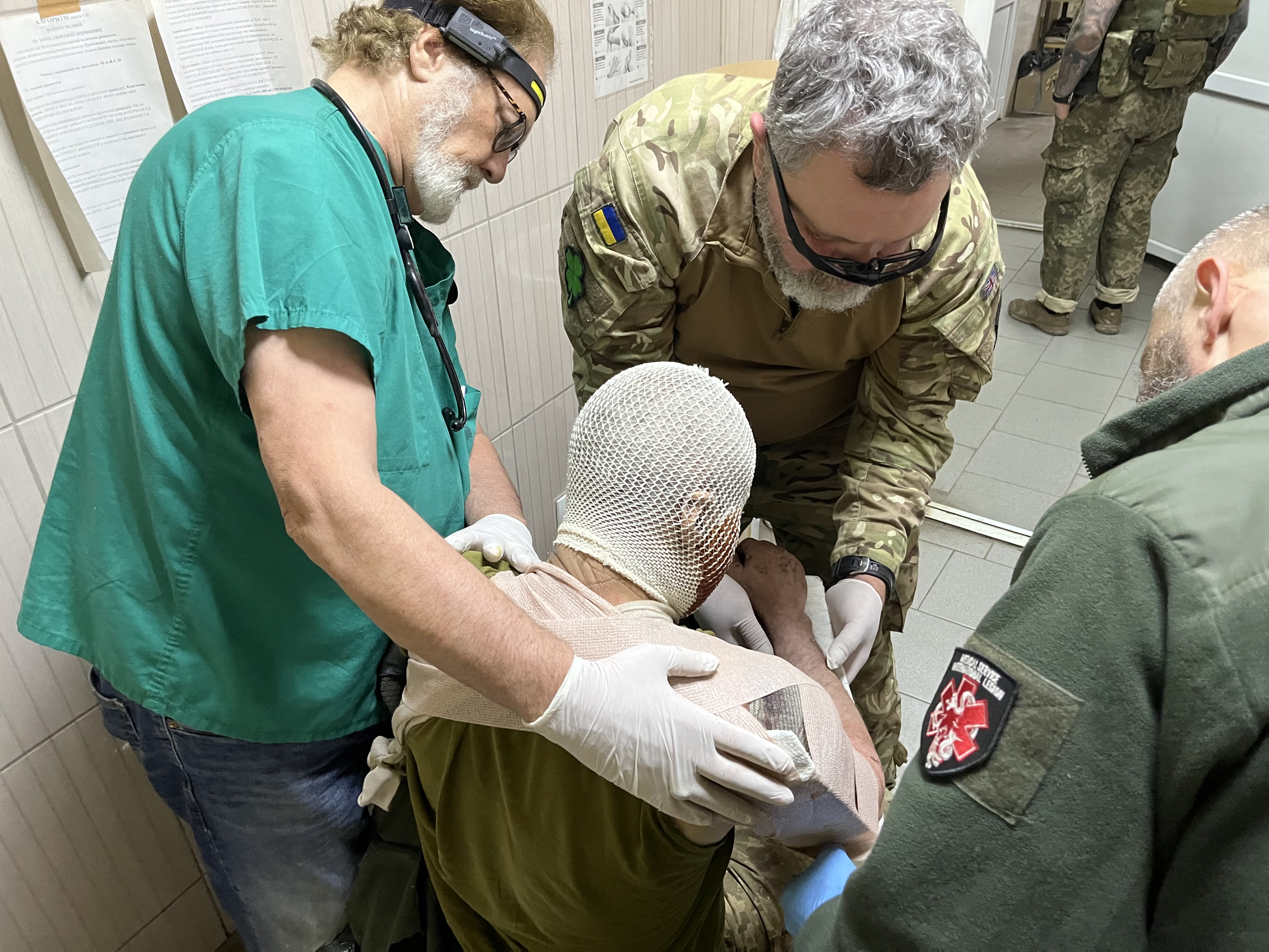 Three medical professionals provide care to a wounded Ukrainian soldier