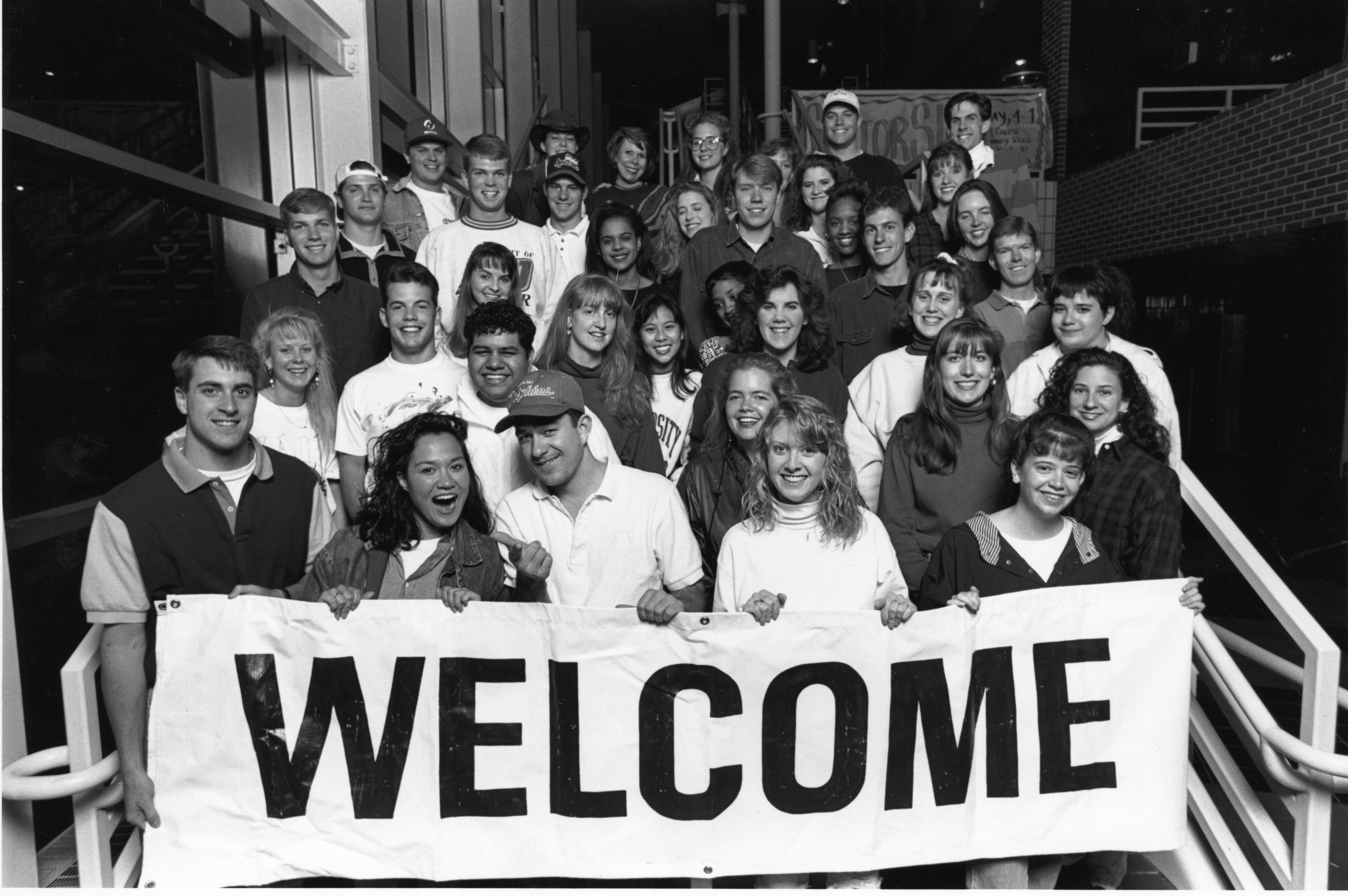 A group of DU students hold a sign that reads "Welcome" 