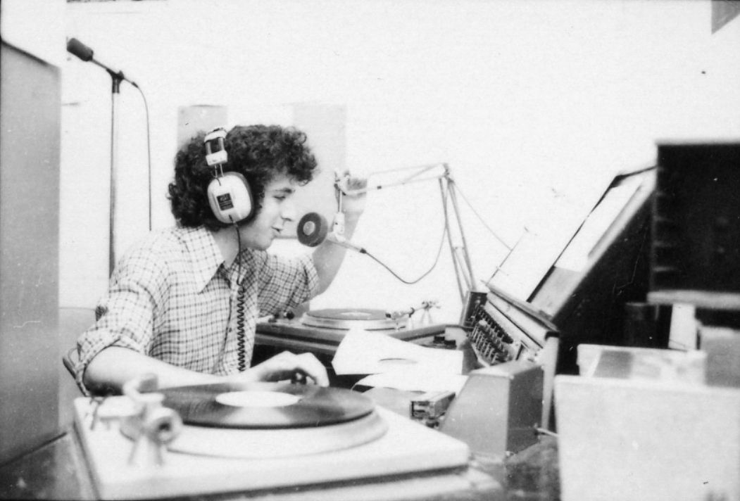 A student spins records and speaks into a microphone