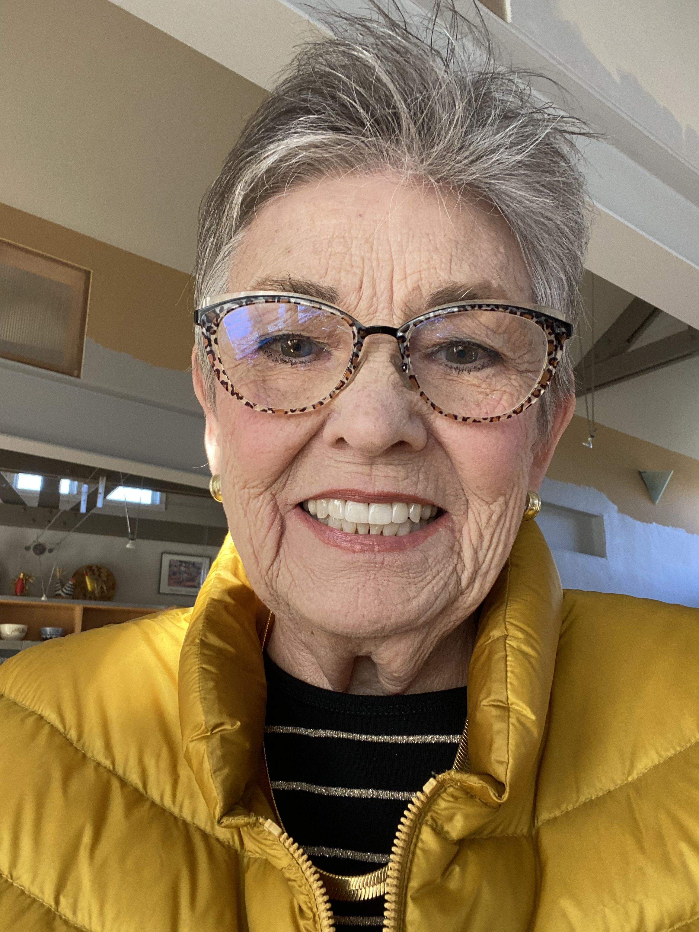 Headshot of Sharon Greenleaf la Pierre wearing a puffy yellow coat and glasses.