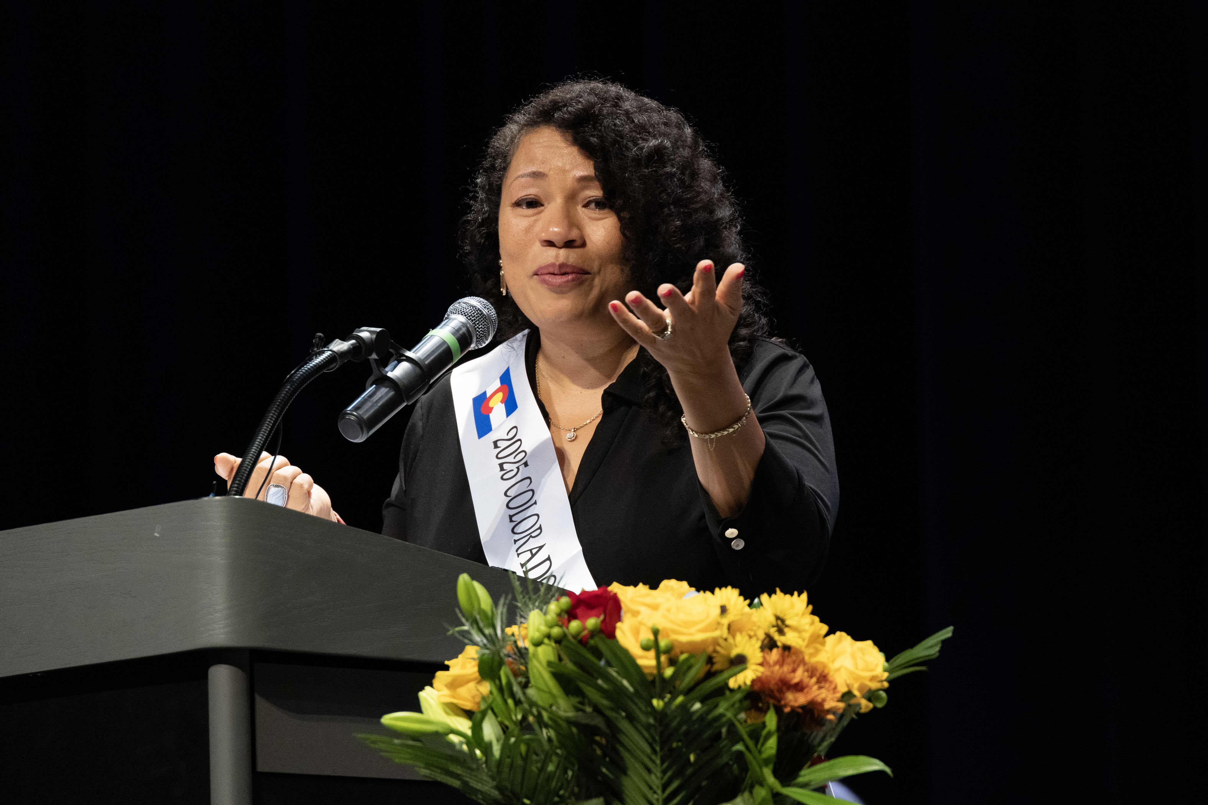 Janet Damon speaks at a podium,. 