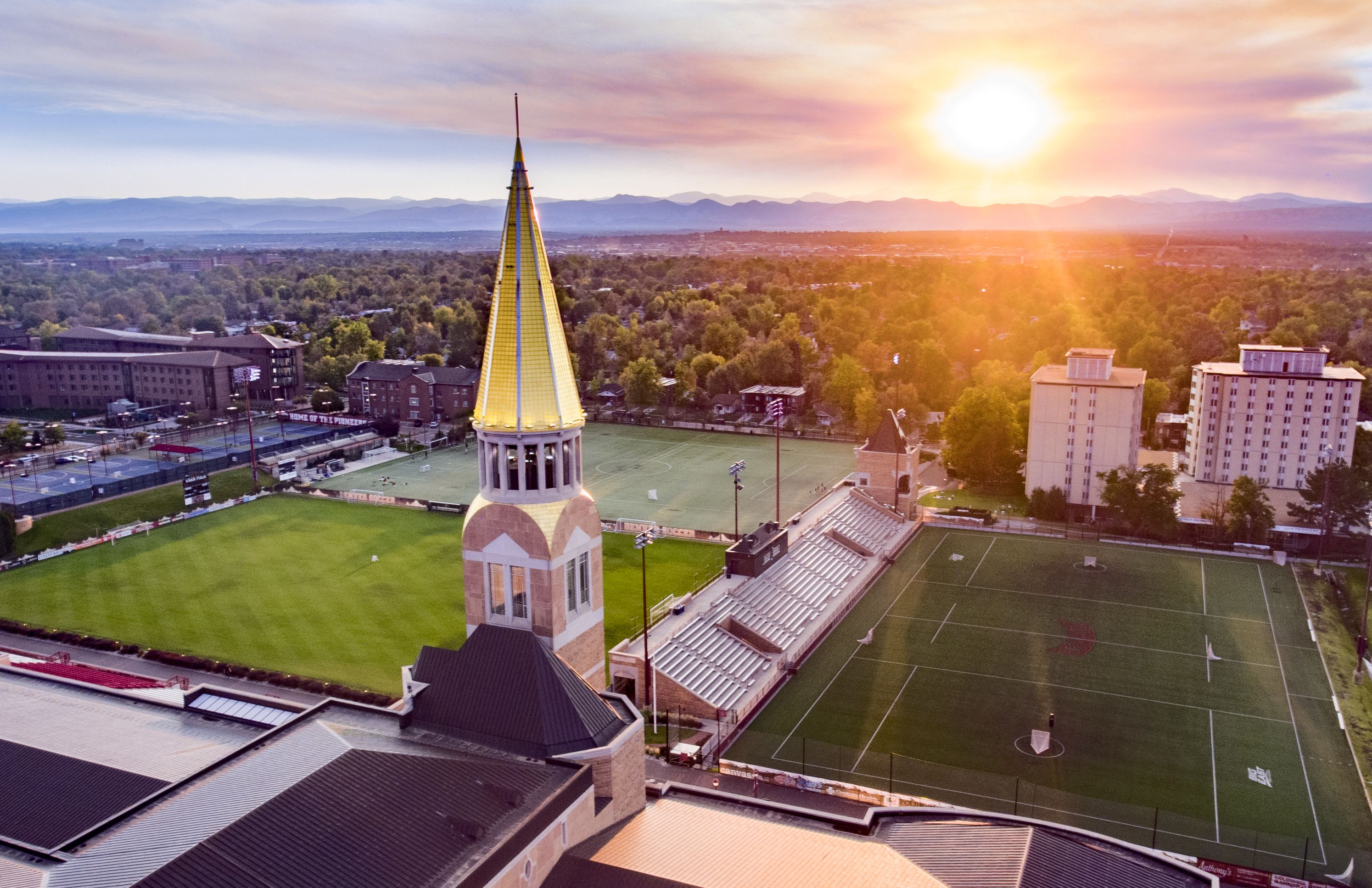 Drone view of DU campus with sun setting behind the Rocky Mountains