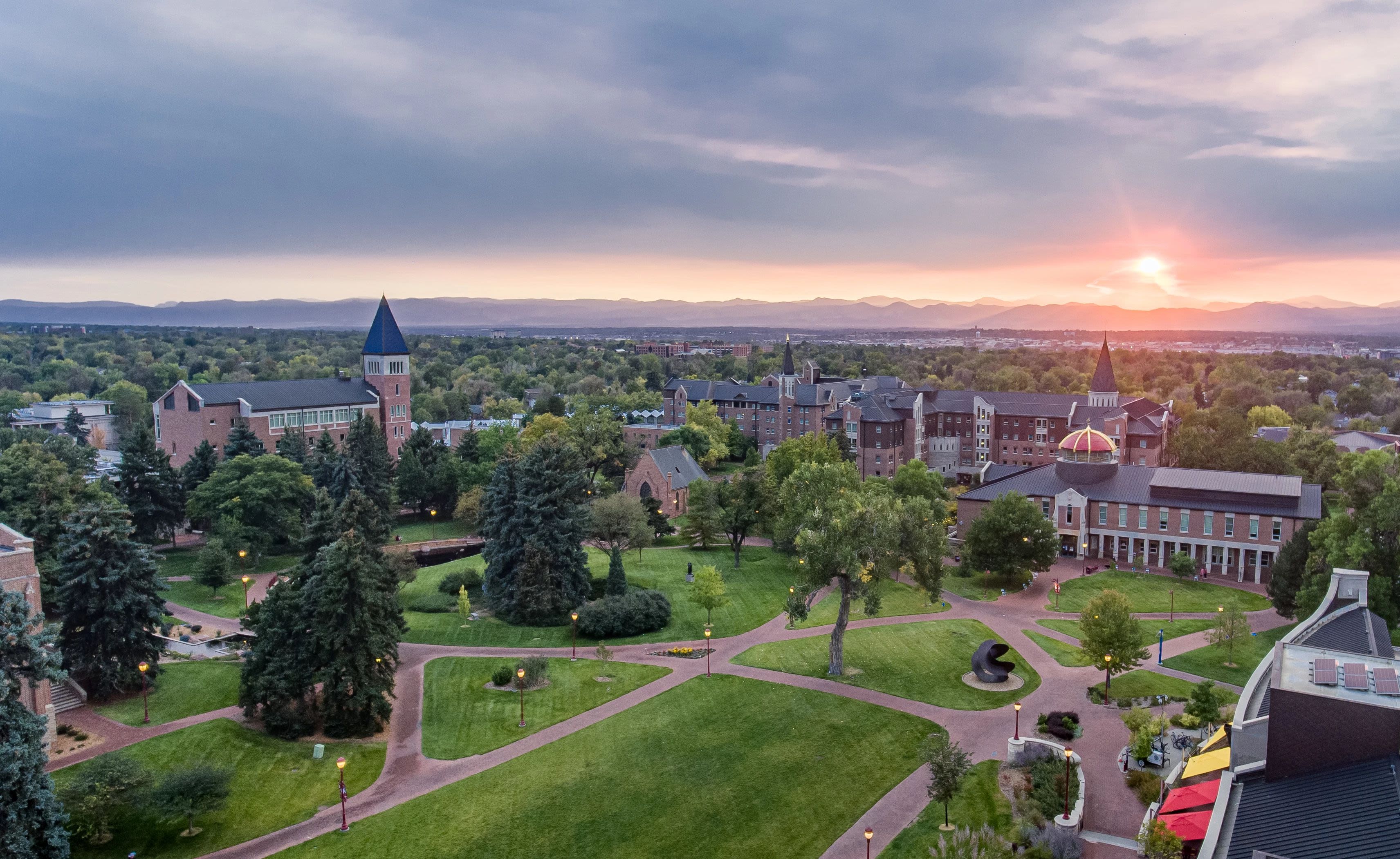 Drone view of DU campus with sun setting behind the Rocky Mountains