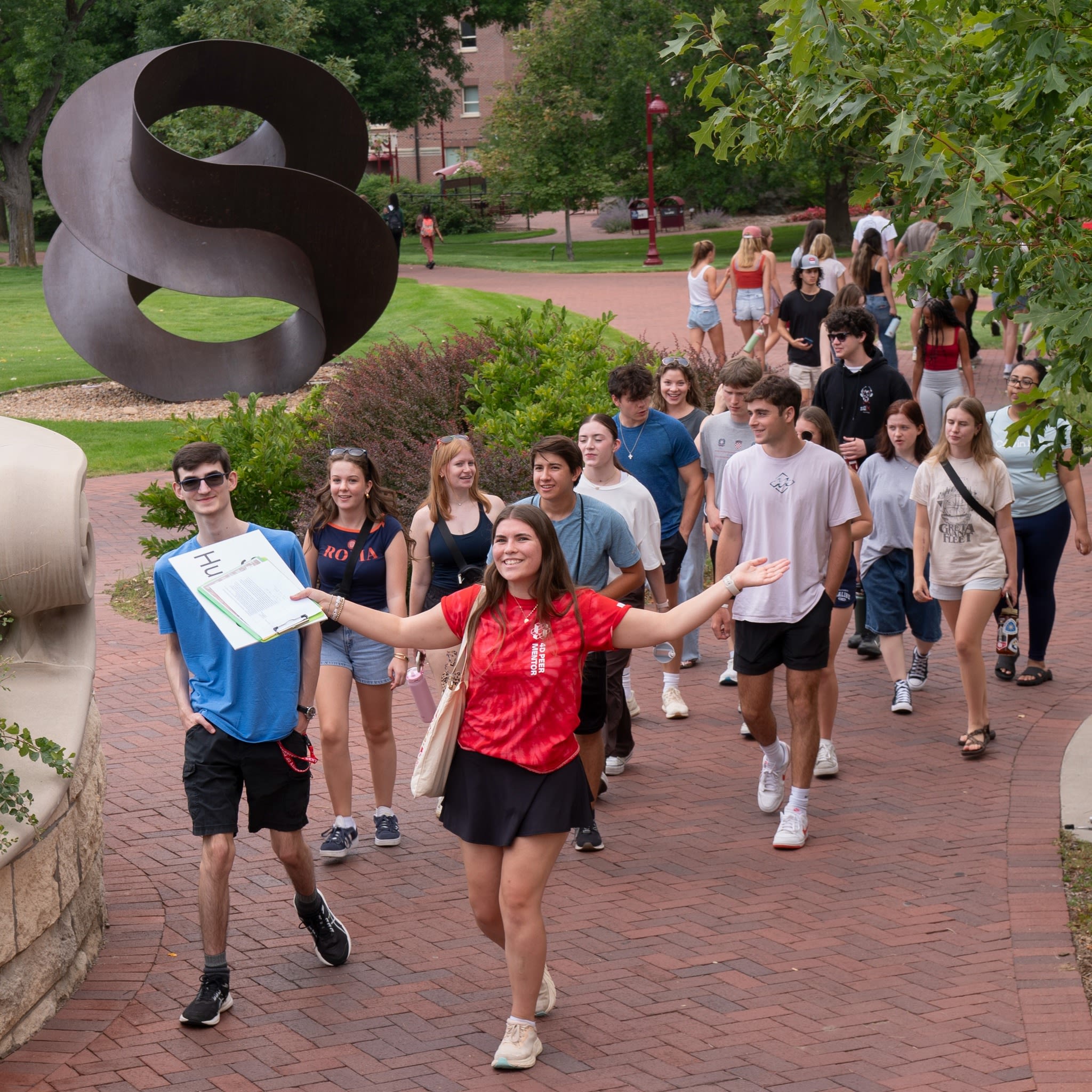 A staff is leading a group of students walking on DU campus