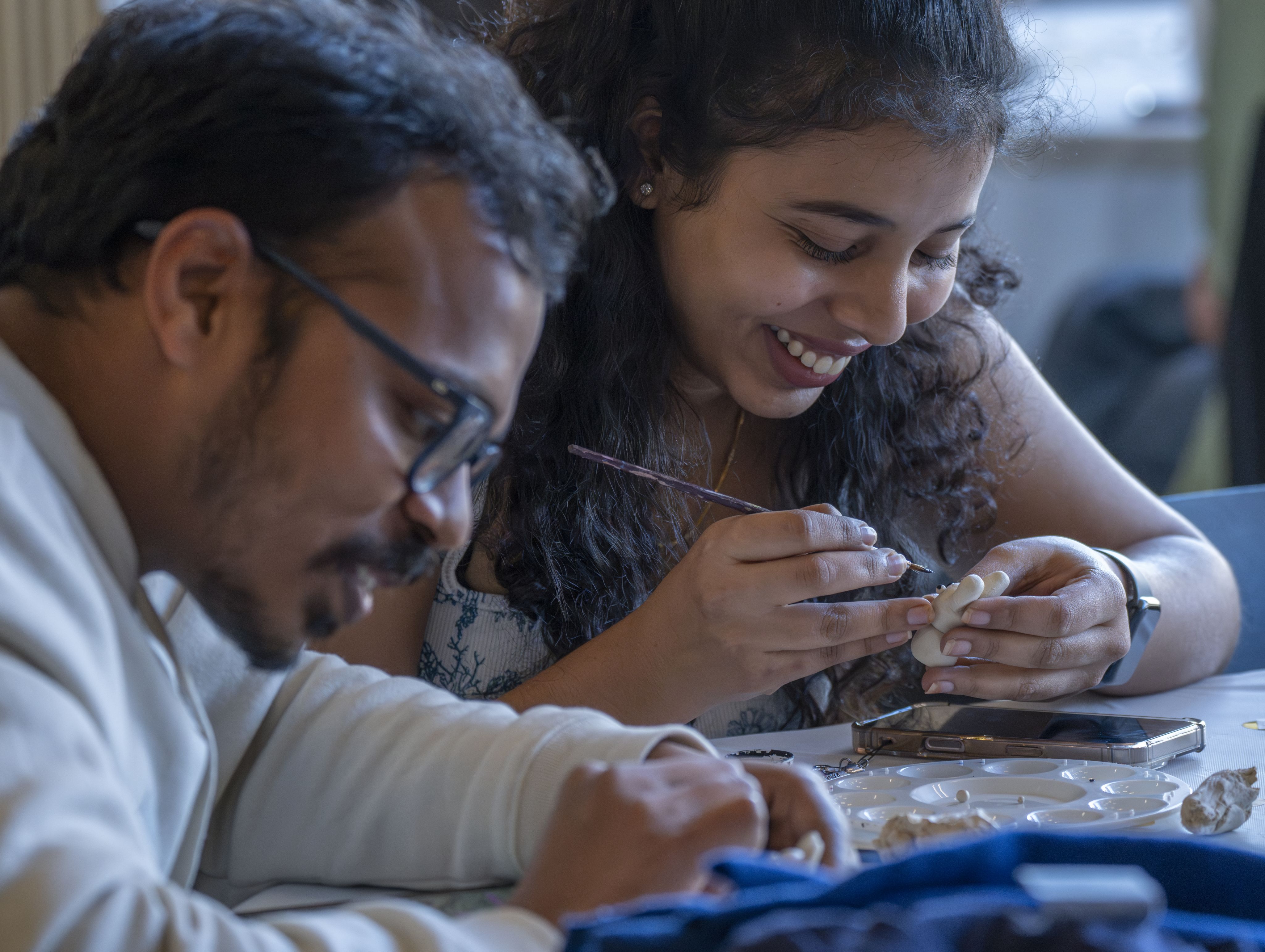 Two students paint trinkets